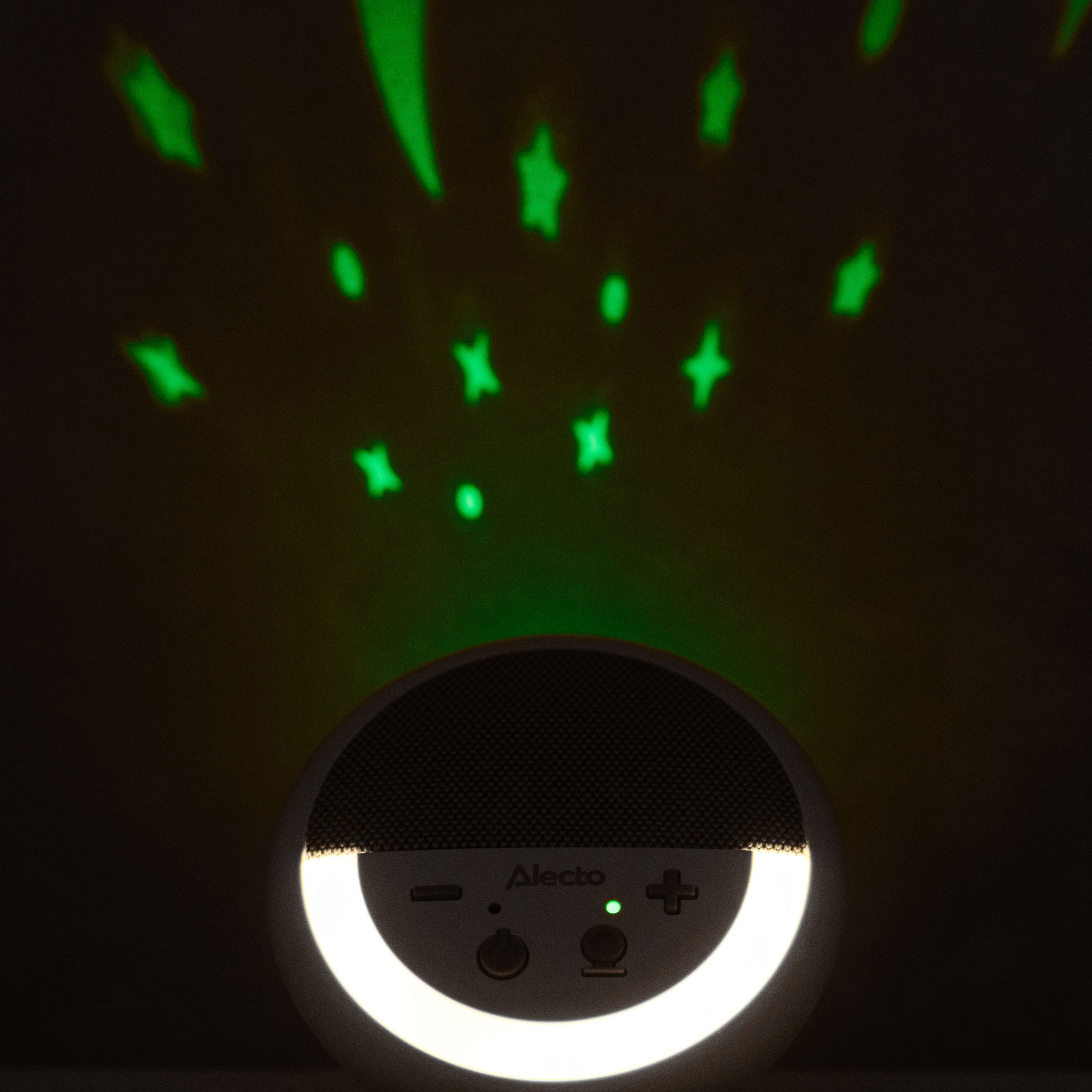 Projecteur de veilleuse pour bébé blanc avec des projections d'étoiles vertes sur fond sombre.
