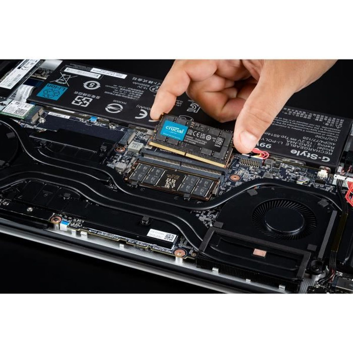 Ręka instalująca moduł RAM Crucial w laptopie.
