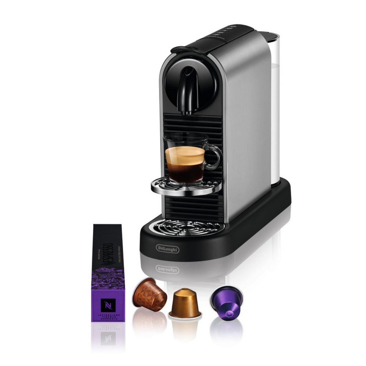 Cafetera espresso plateada con taza, cápsulas y depósito de agua.