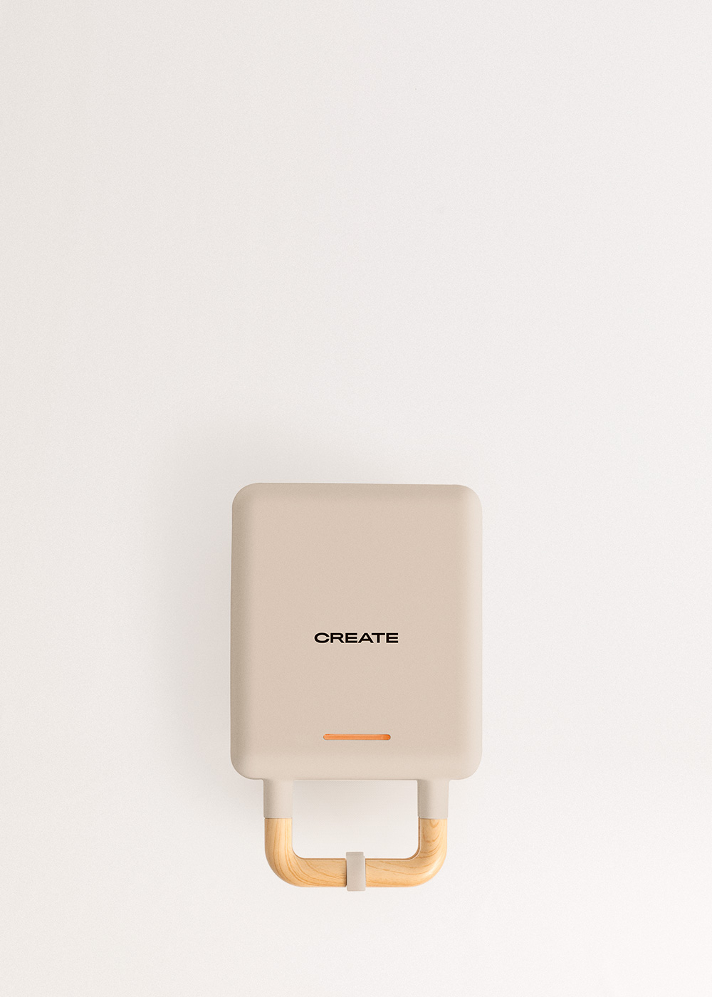 Una gofrera color beige con asa de madera, con la palabra "CREATE" escrita en el frontal.
