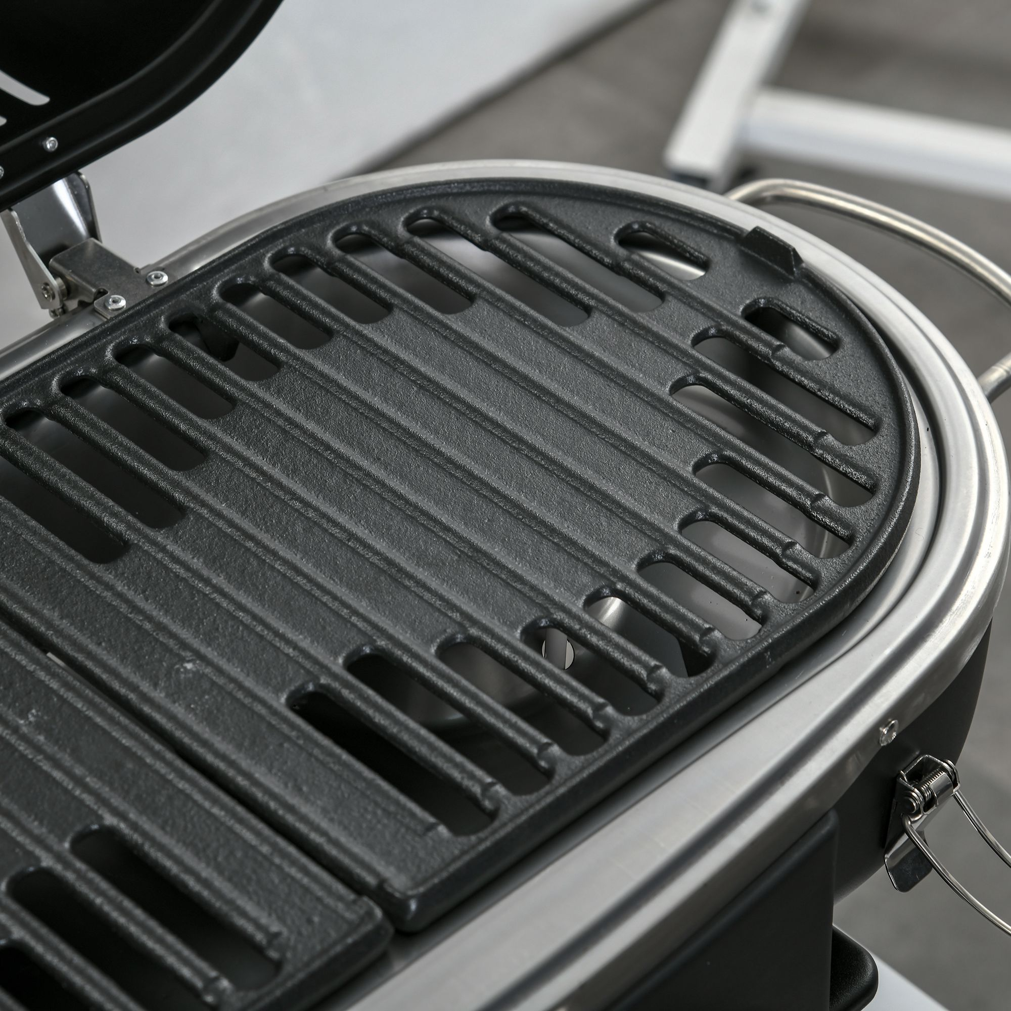 Nahaufnahme eines schwarzen Grillrosts in einem tragbaren Grill. Metallgriff sichtbar.