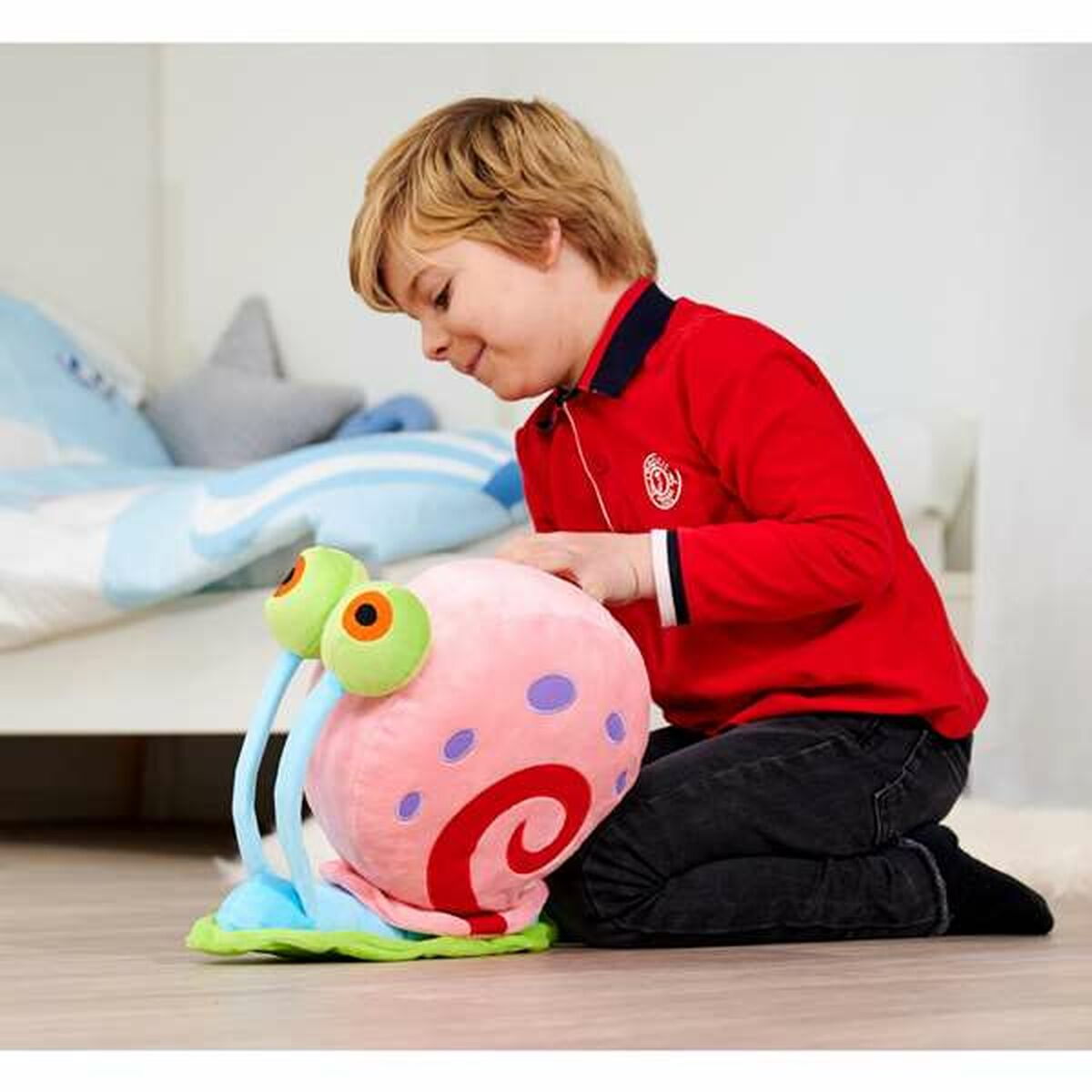 Un ragazzino in ginocchio accarezza Gary, la lumaca di peluche rosa di Spongebob.