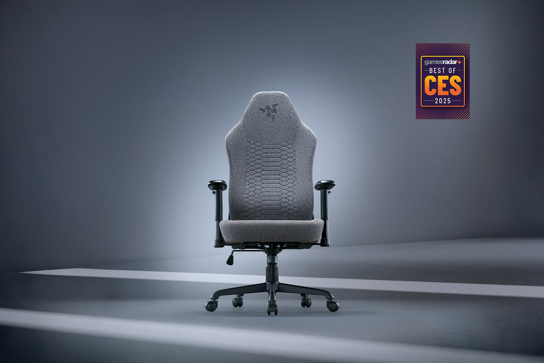 Gri Razer oyun koltuğu, önden görünüm, GamesRadar+ Best of CES rozeti ile stüdyo arka planında.