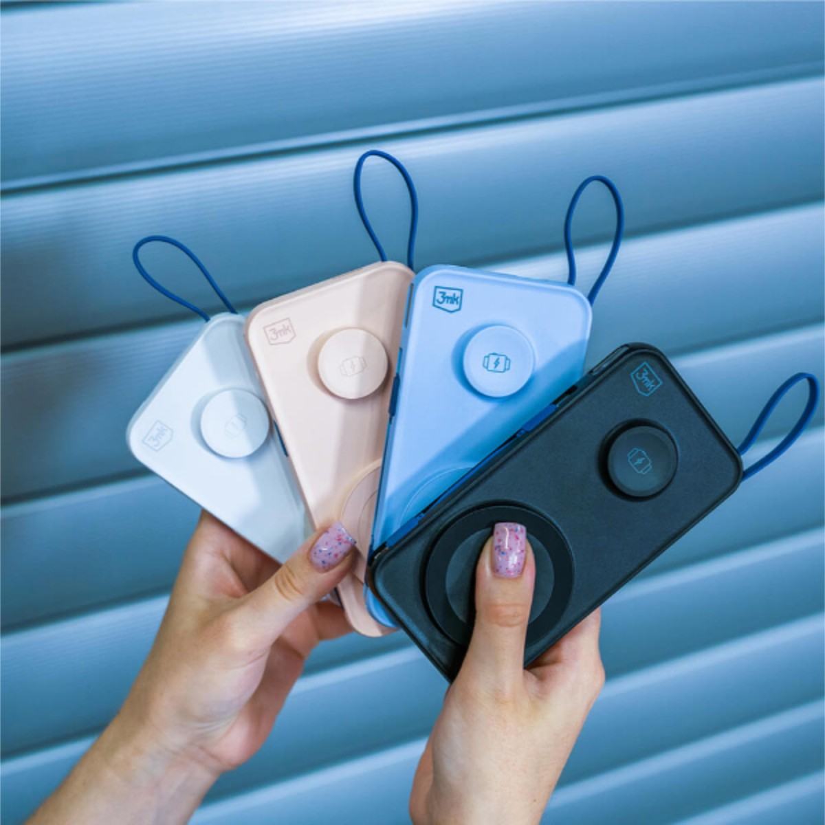 Cztery power banki w różnych kolorach trzymane w dłoniach.