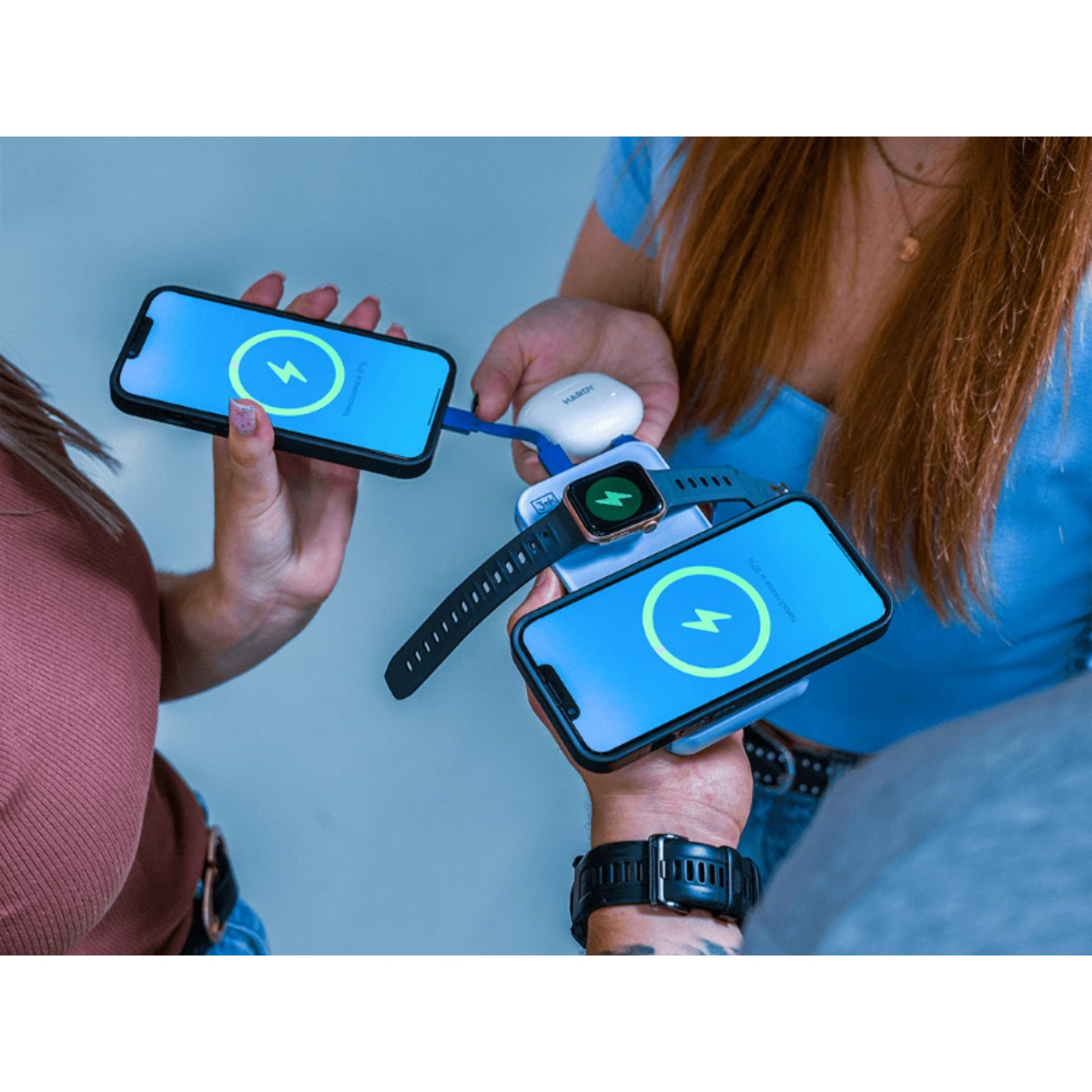 Dwa telefony i zegarek ładują się na power banku.