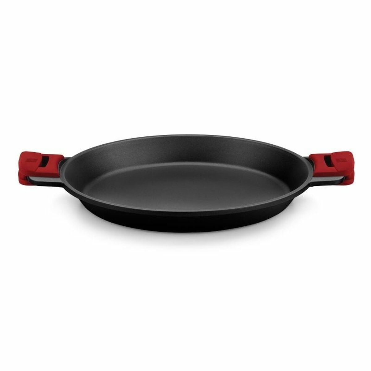 Schwarze Bratpfanne mit roten Griffen. Sie ist leer und auf einer weißen Oberfläche platziert.