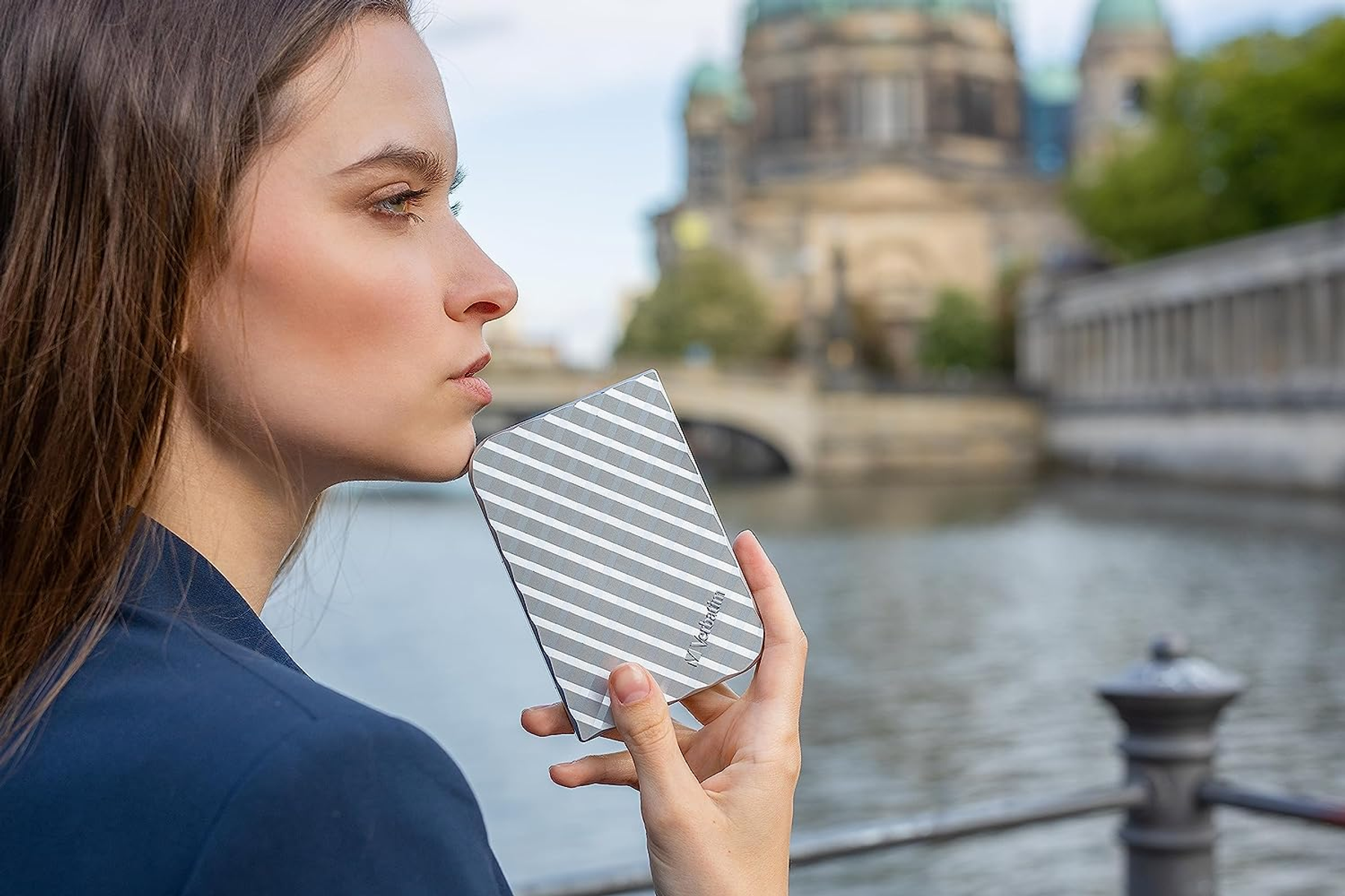 Kobieta trzymająca dysk twardy nad rzeką, z rozmytym tłem miasta.