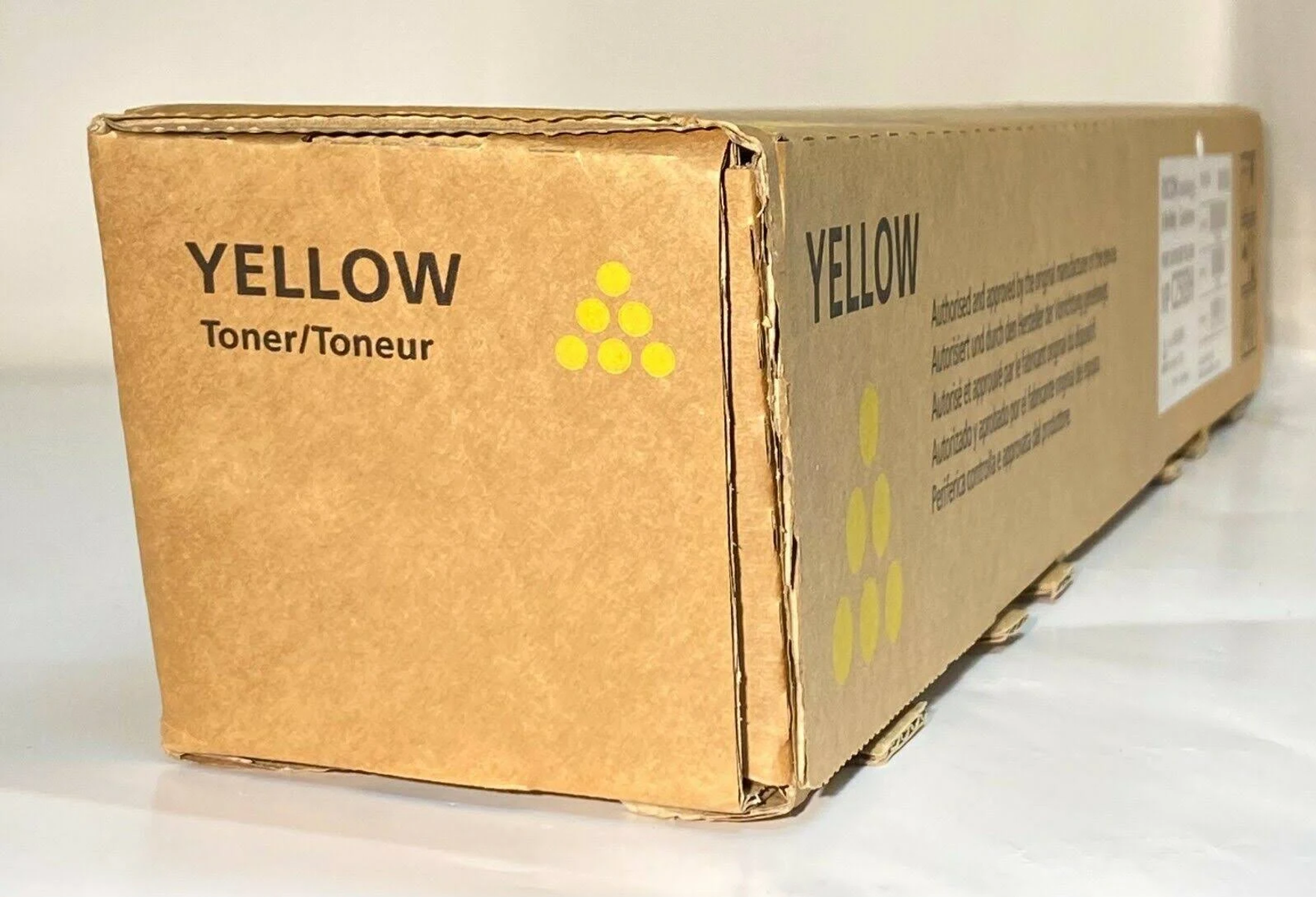 Een gele tonercartridge doos met het woord YELLOW en YELLOW toner/toneur erop geschreven.