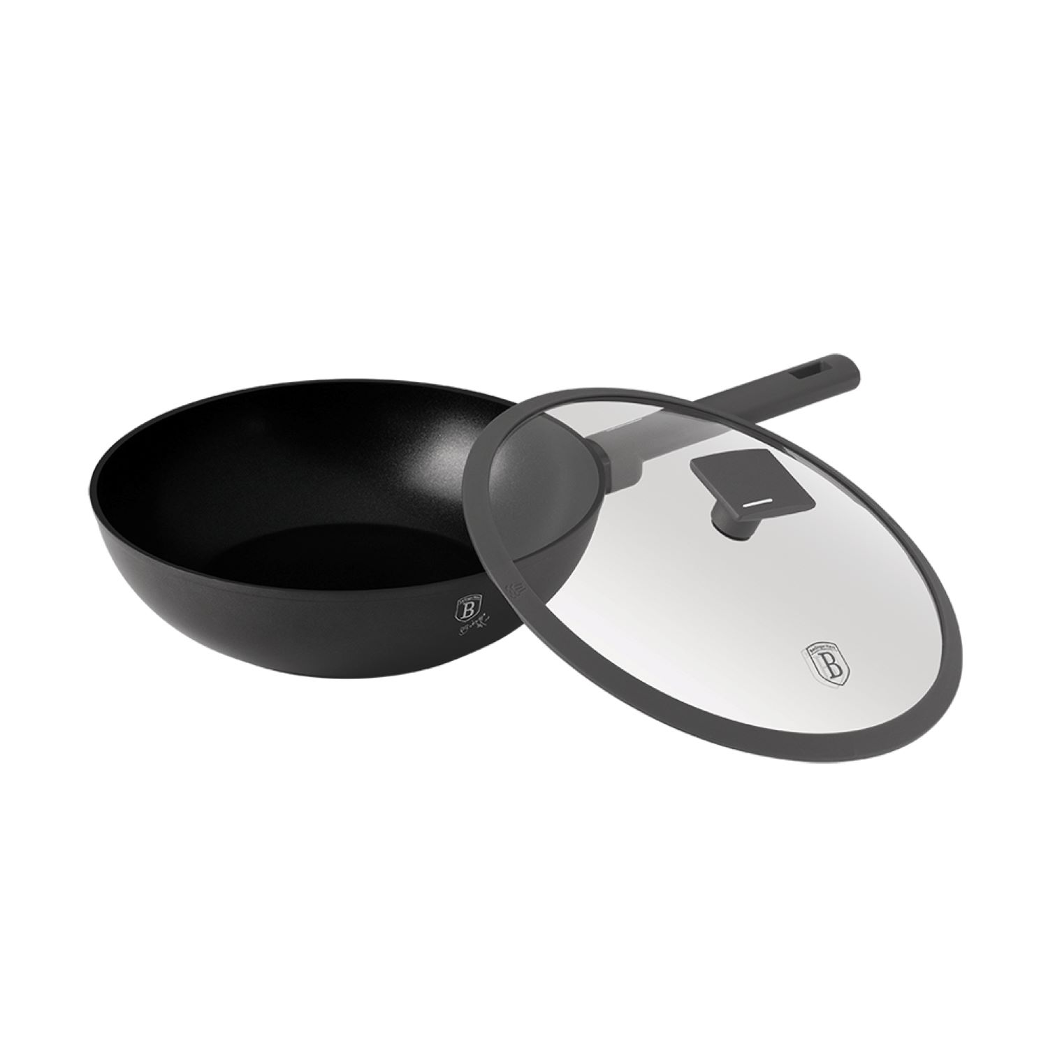 Poêle wok noire avec couvercle en verre et poignée. Le couvercle est à côté de la poêle.