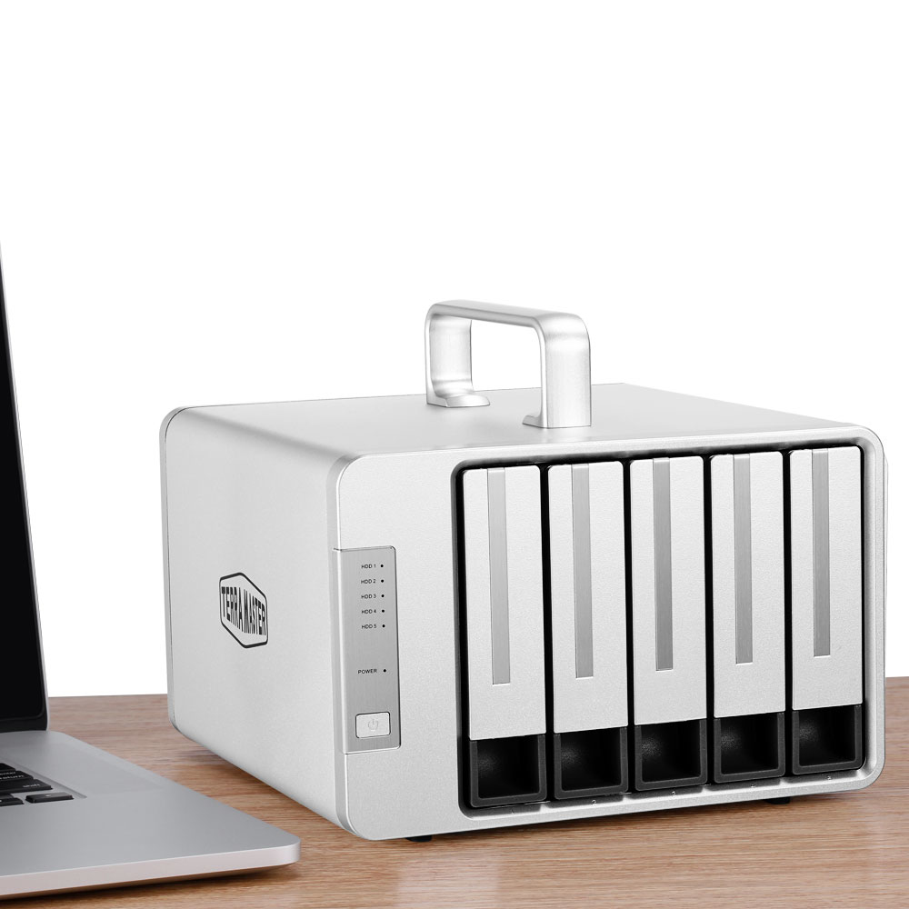 Dispositivo NAS argentato con maniglia e cinque slot, un laptop sullo sfondo.