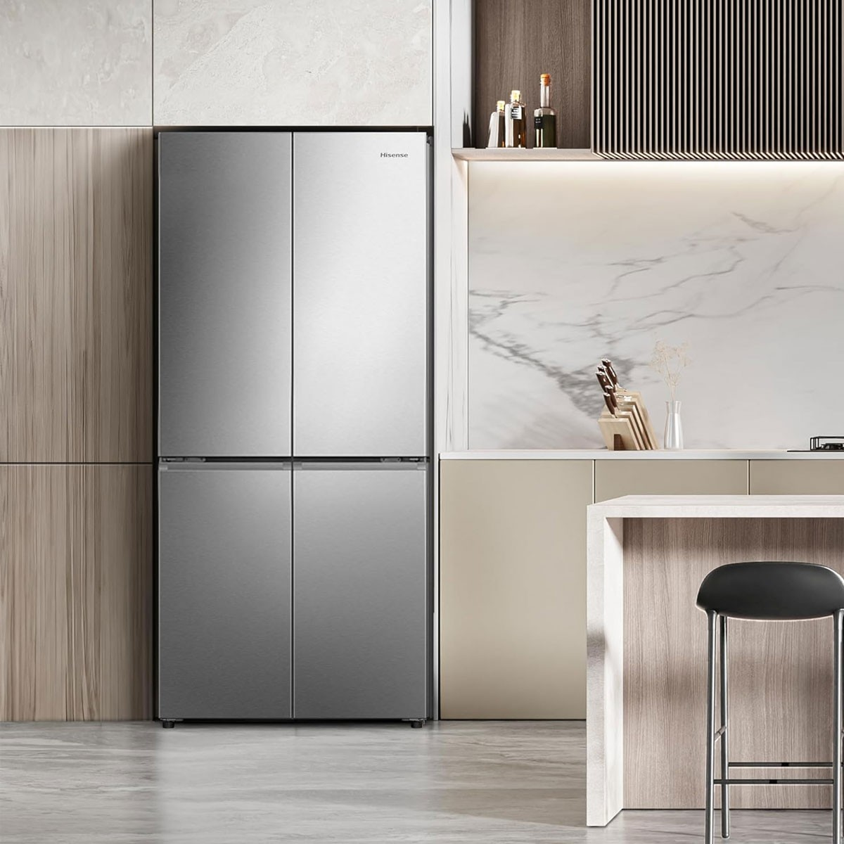 Refrigerador Hisense plateado con cuatro puertas. En una cocina con pared de madera e isla.