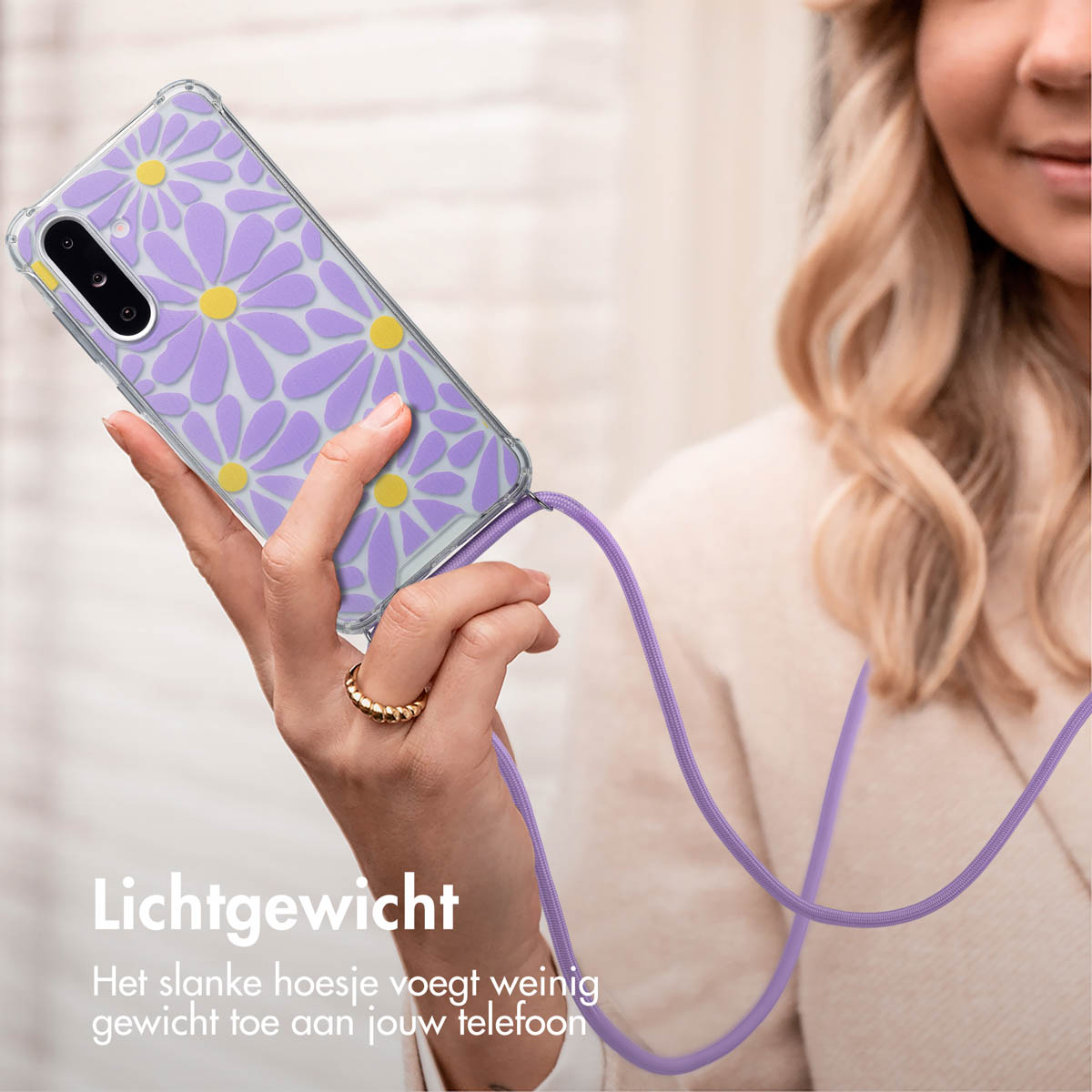 Vrouw die een telefoon met een paars madeliefhoesje vasthoudt. De telefoon hangt aan een paarse koord. Ring.