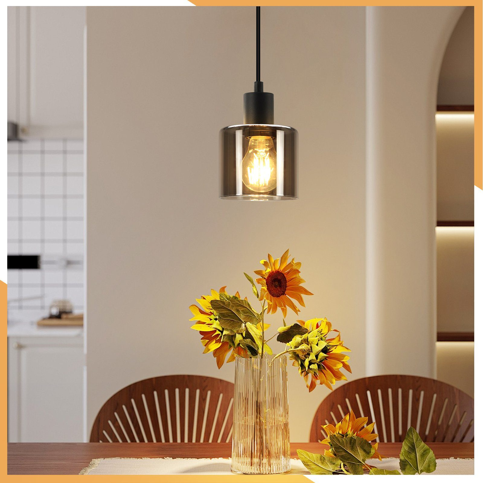 Lampada a sospensione con lampadina, girasoli in un vaso su un tavolo. Due sedie sullo sfondo.