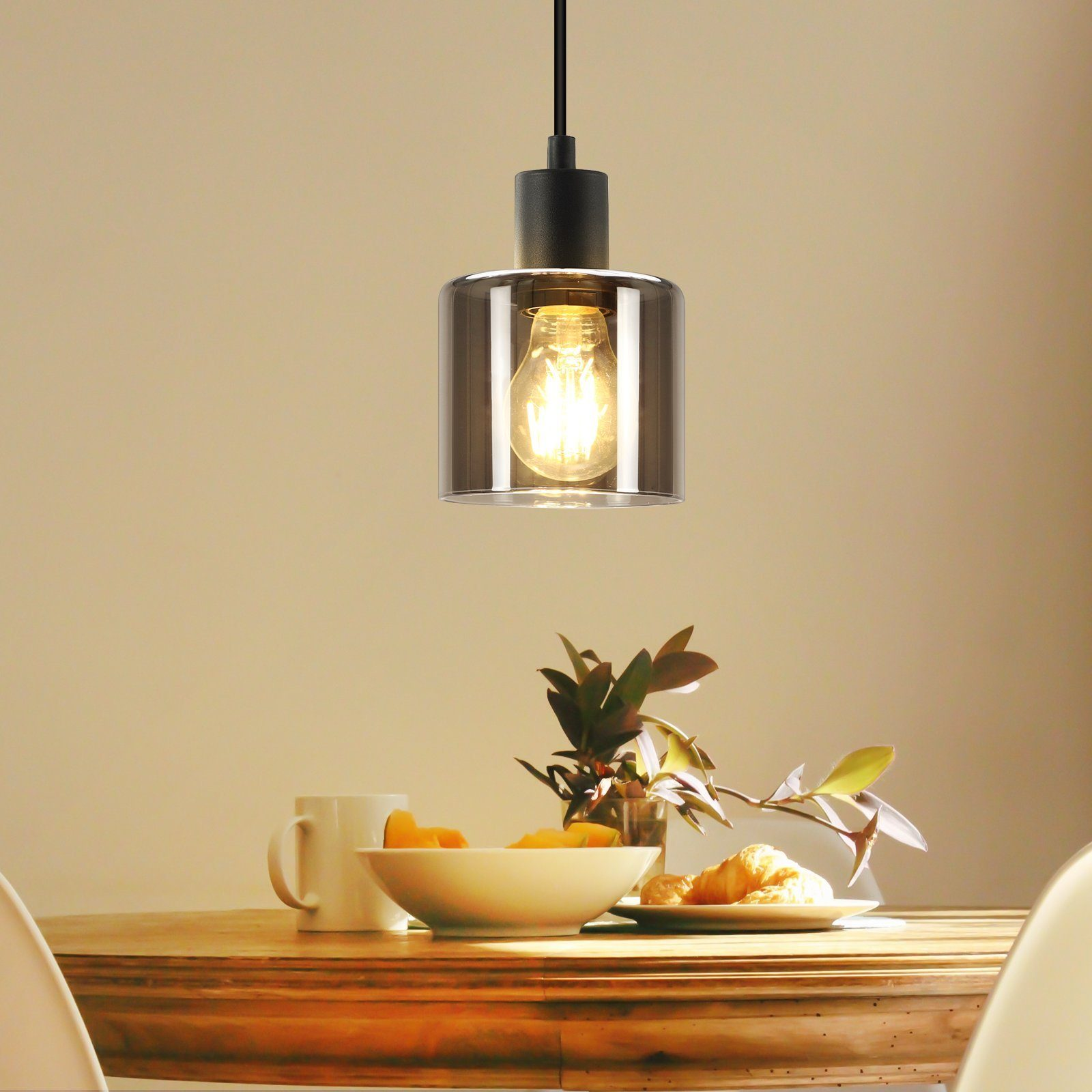 Lampa wisząca nad stołem z jedzeniem. Lampa ma przezroczysty szklany klosz.