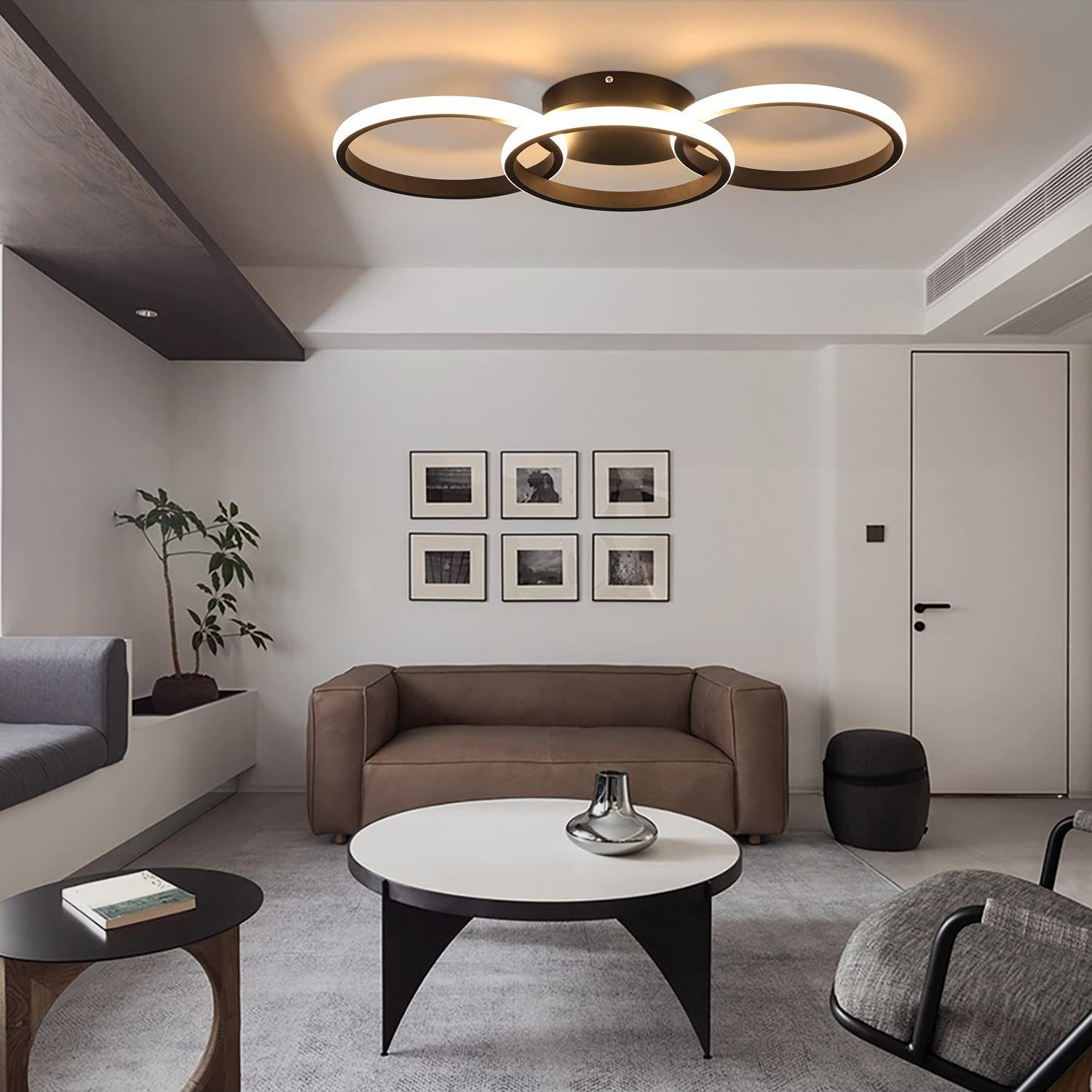 Lampa sufitowa z trzema połączonymi okrągłymi światłami, w nowoczesnym salonie.