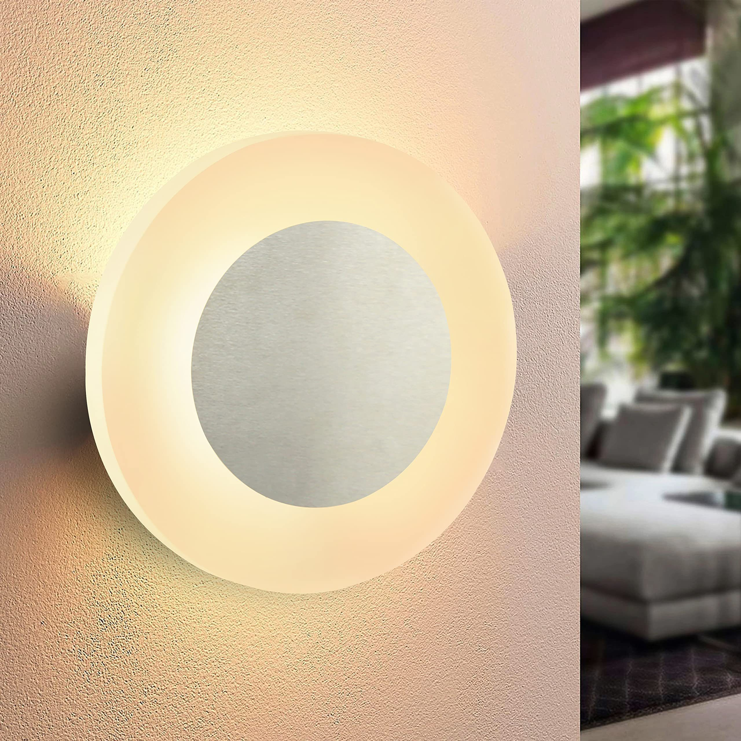 Lampada da parete rotonda con una luce brillante. Ha un disco metallico centrale e un anello di luce intorno.