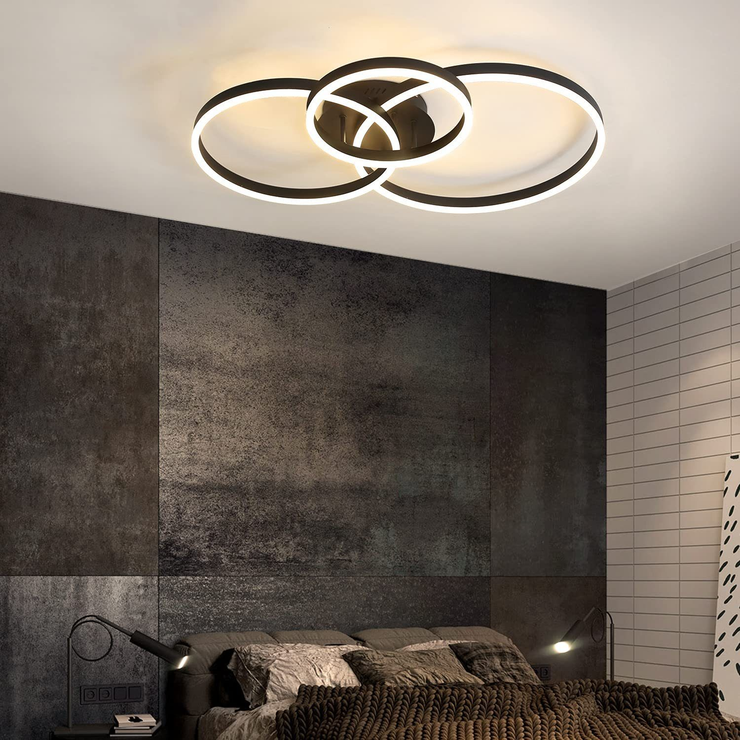 Schwarze Deckenleuchte mit ineinandergreifenden Ringen. Der Raum hat eine dunkle Wand und zwei Lampen.