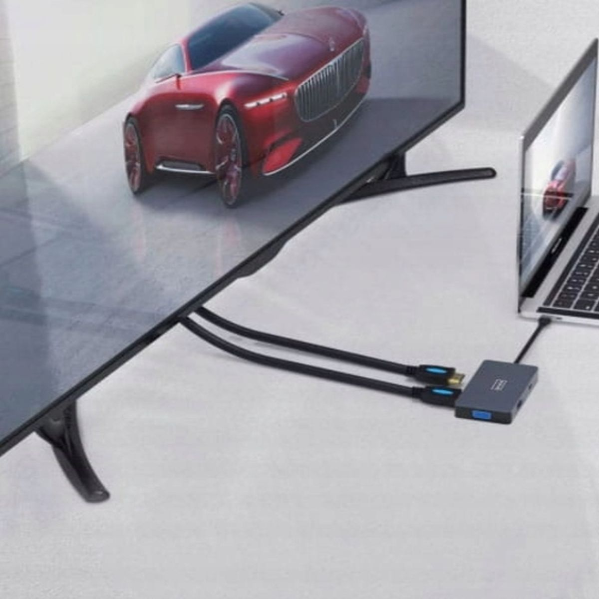 Czerwony samochód jest wyświetlany na dużym ekranie podłączonym do laptopa przez hub.