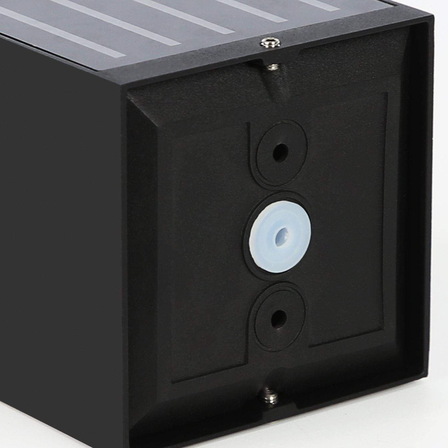 Primo piano di un cubo nero. Mostra fori per viti e un pezzo di plastica bianca.