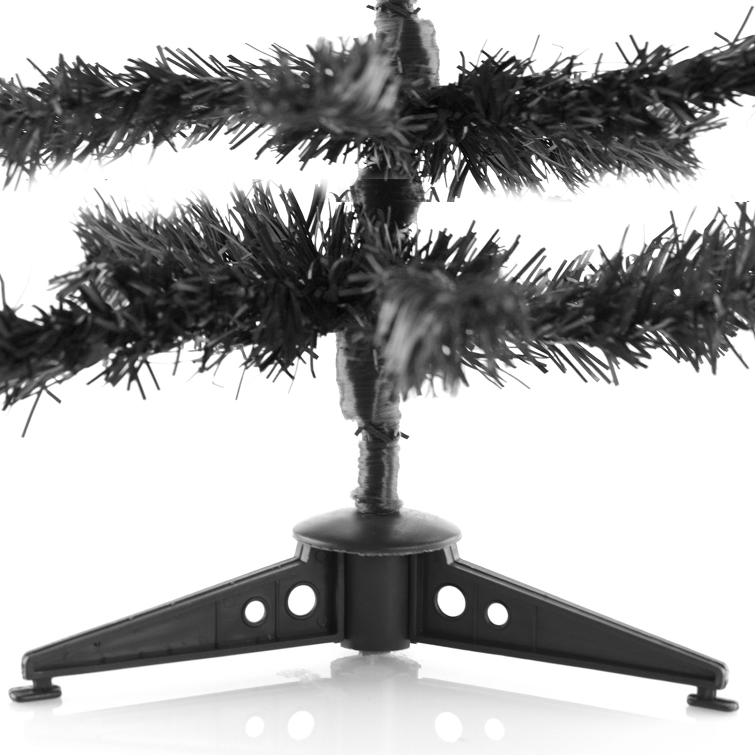 Soporte negro para árbol de Navidad con tres patas. Ramas oscuras y esponjosas se extienden.