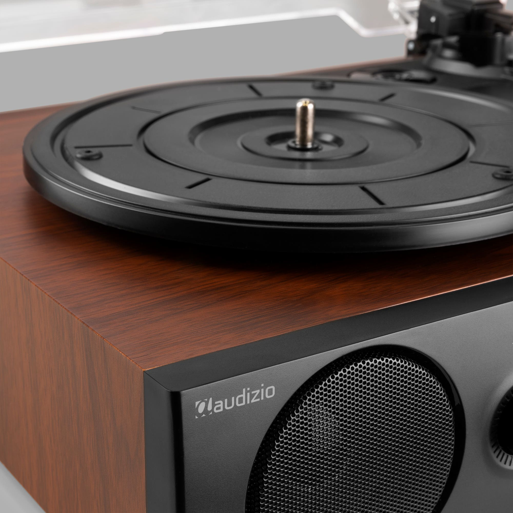 Close-up of a turntable. The turntable has a wooden finish and a black speaker.