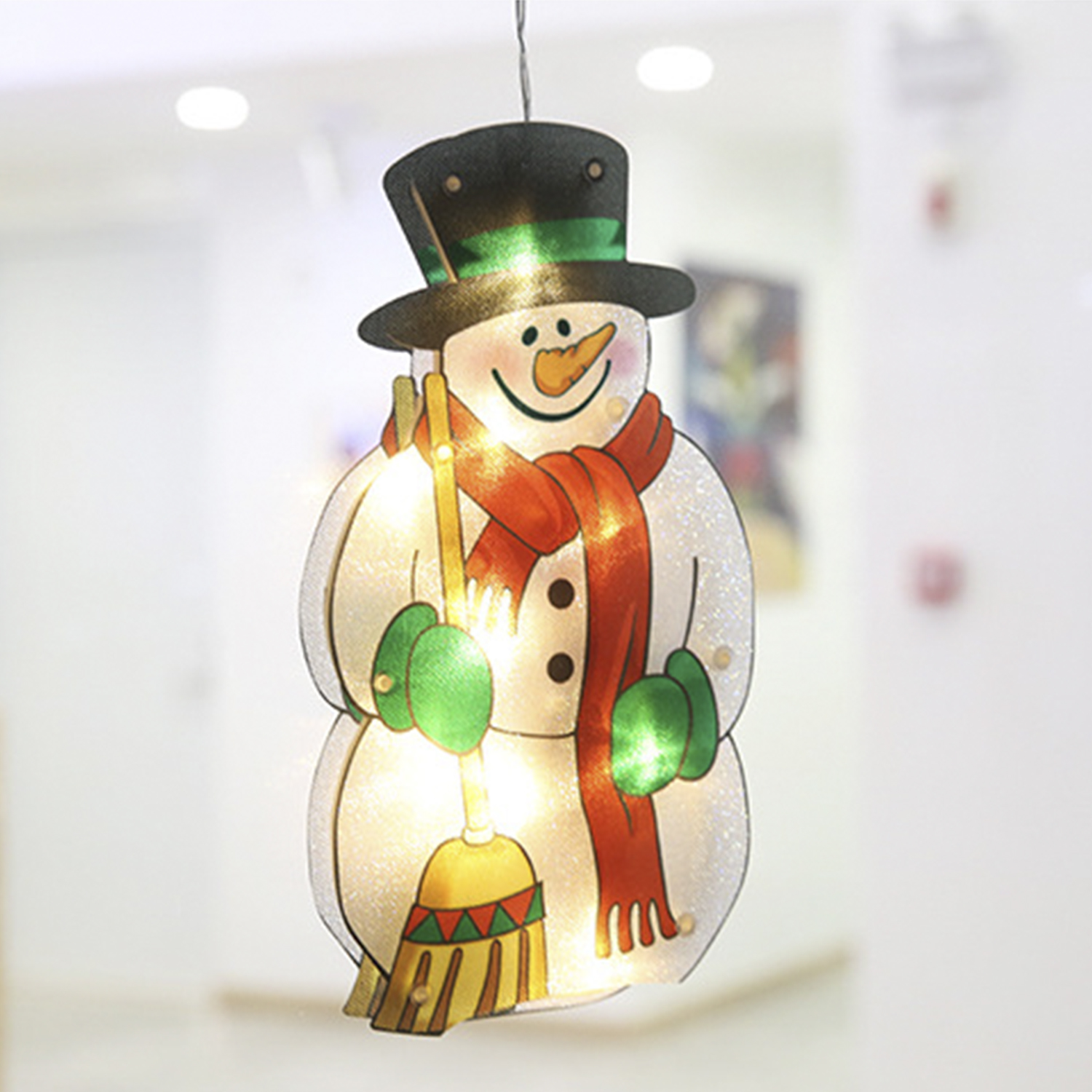 Una decorazione a forma di pupazzo di neve illuminato con naso di carota, sciarpa e scopa.