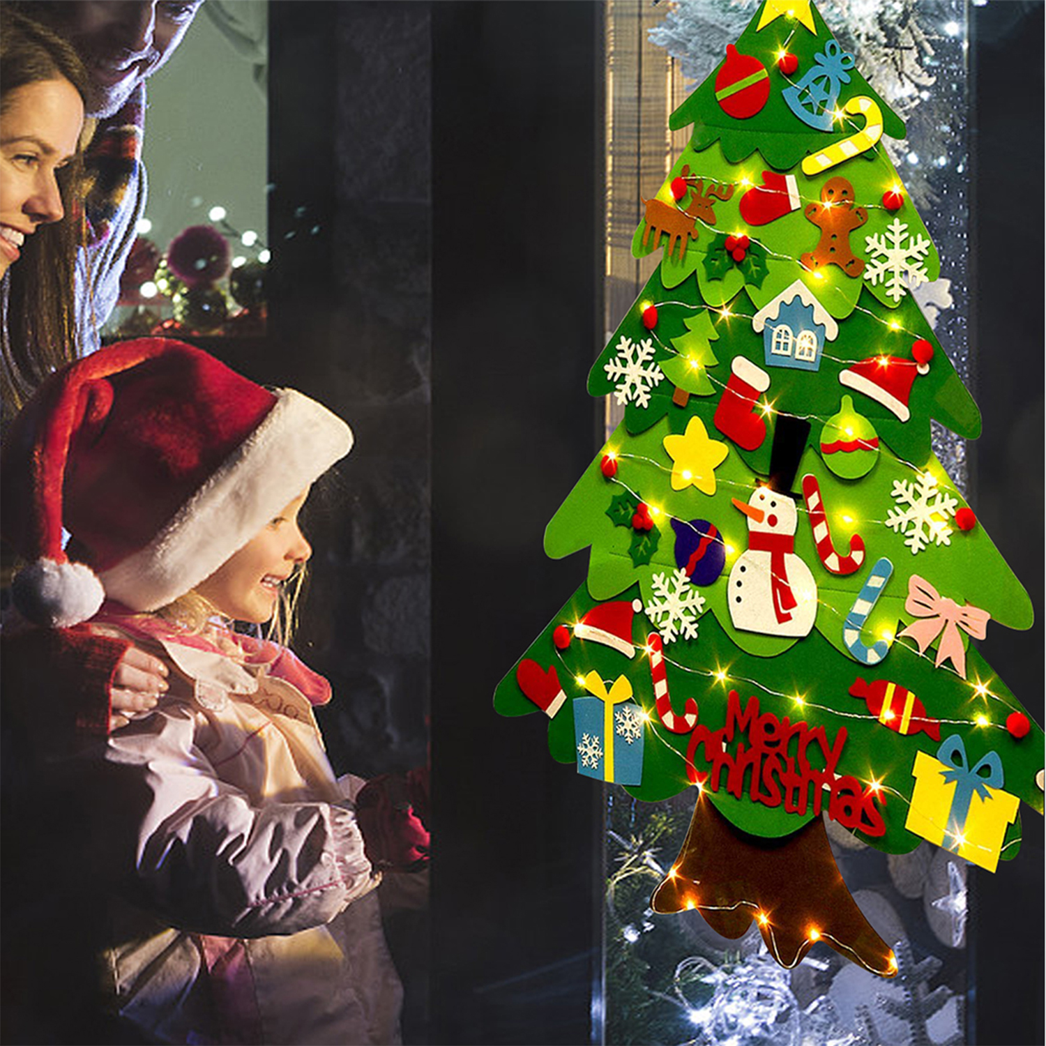 Una niña y una mujer mirando un árbol de Navidad de fieltro con decoraciones.