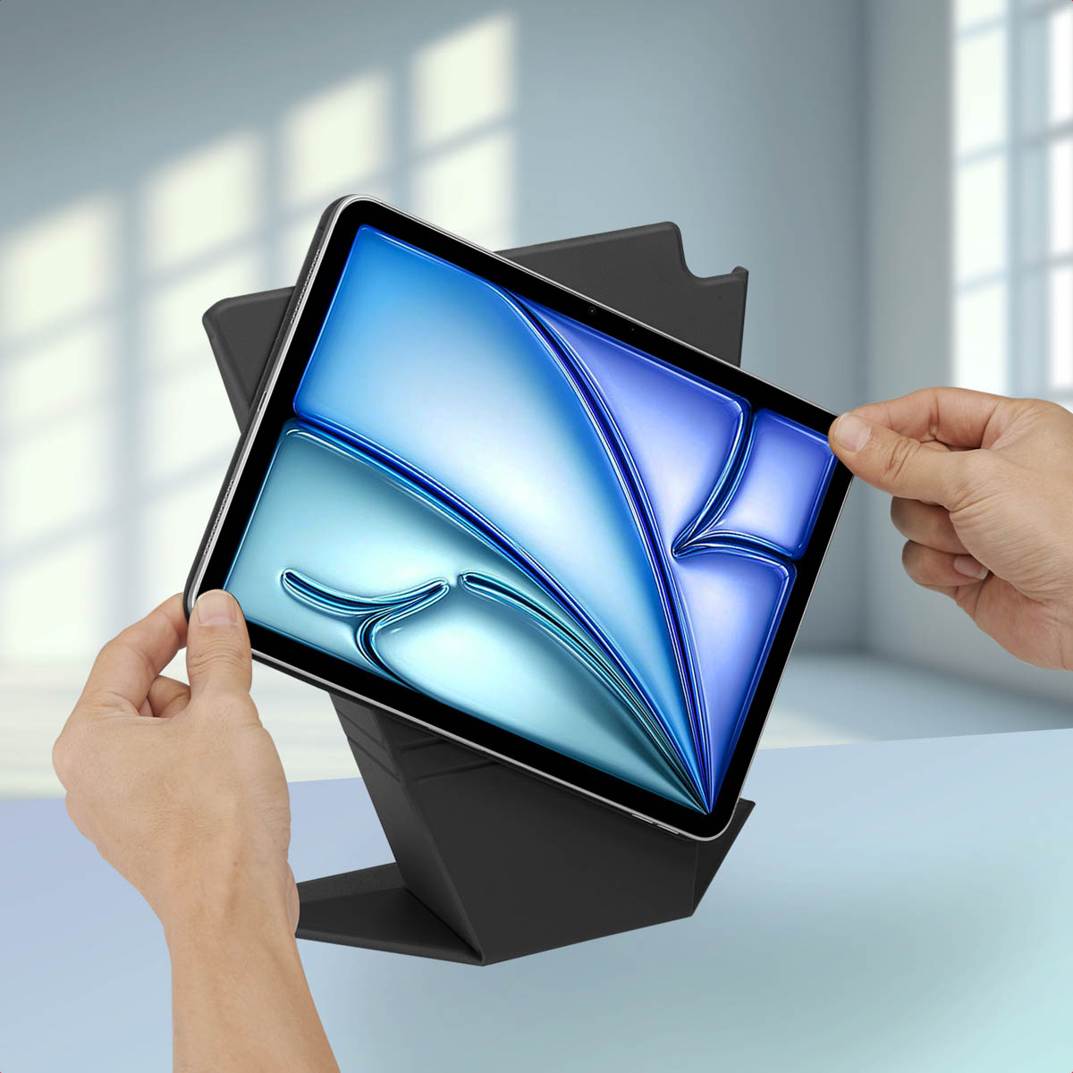 A tablet held in a stand, hands are holding the tablet and the stand.