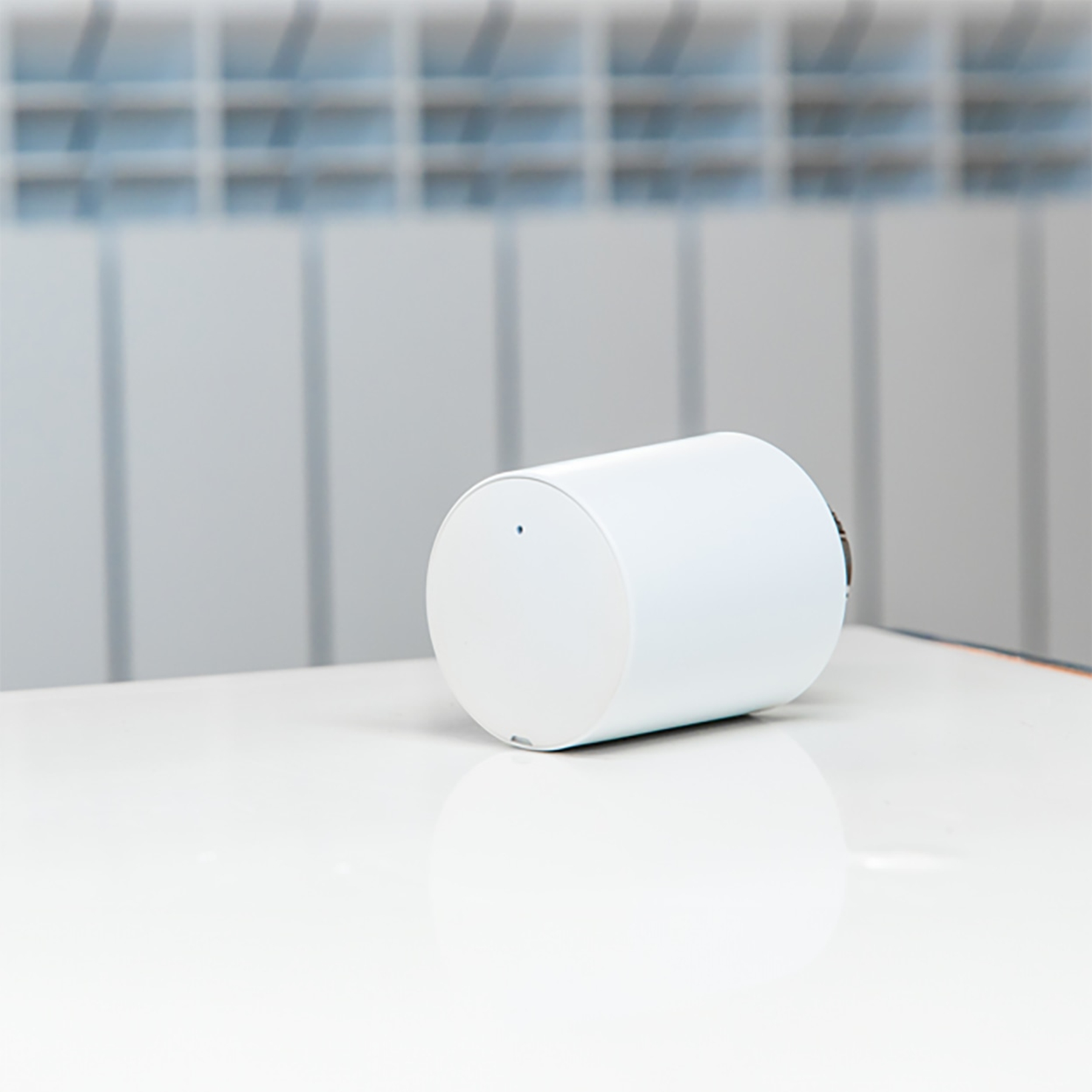 Białe cylindryczne urządzenie smart home na białej powierzchni.