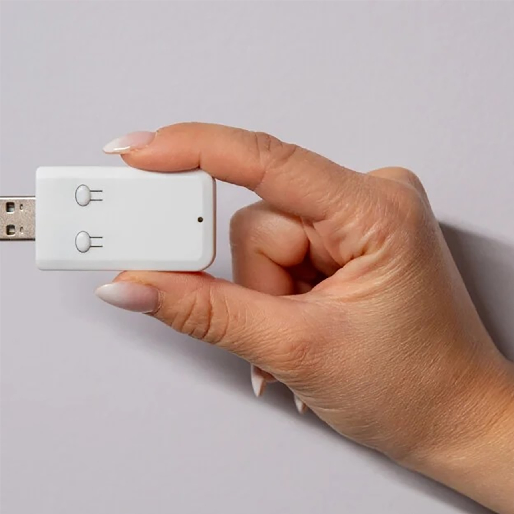 Dłoń trzymająca białą przejściówkę USB z dwoma przyciskami.