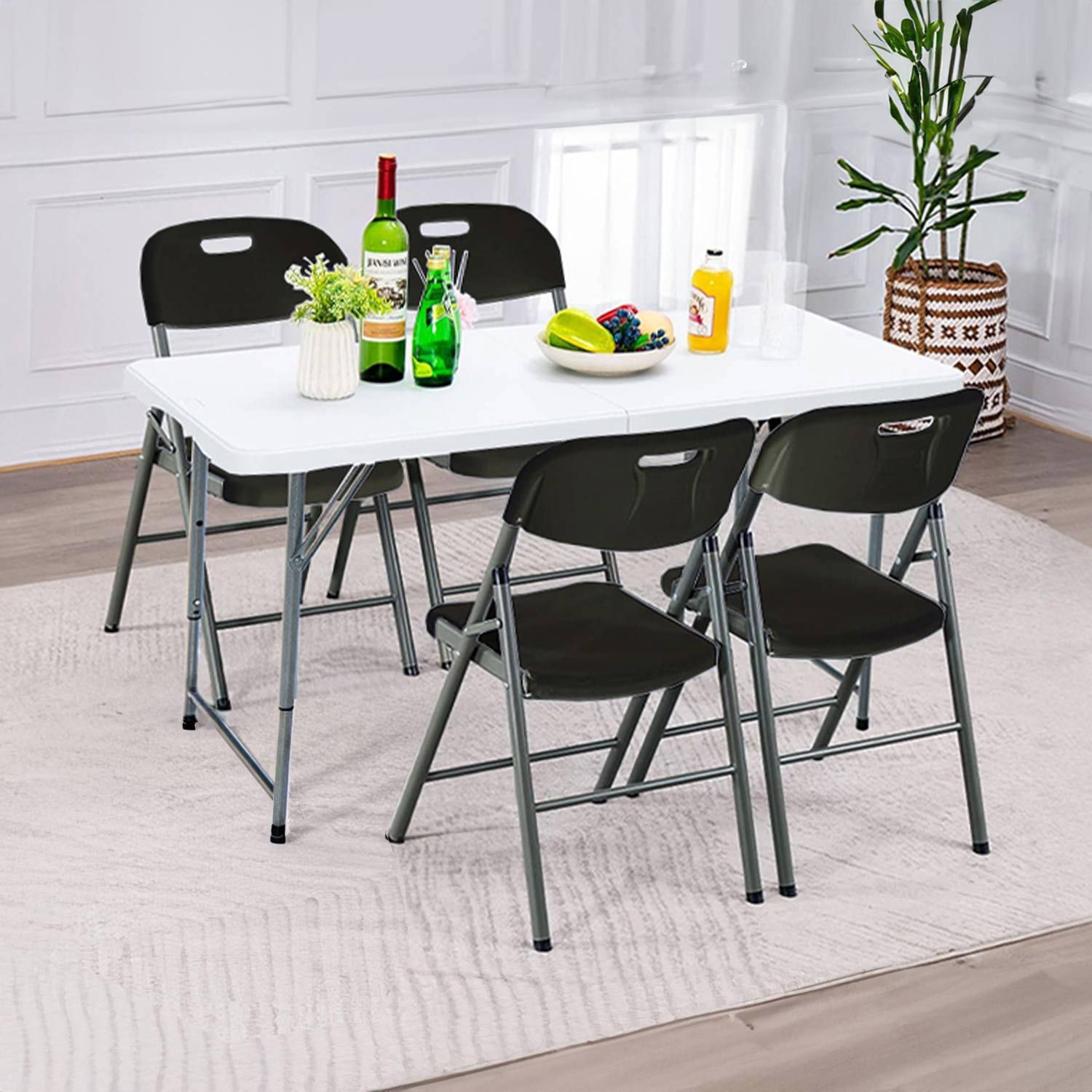 Mesa con sillas negras, comida y bebidas. Una planta de fondo.