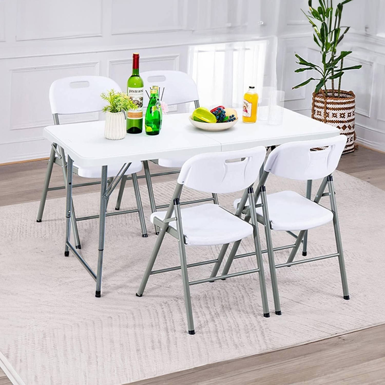 Mesa blanca con cuatro sillas y una planta. El fondo es una habitación.
