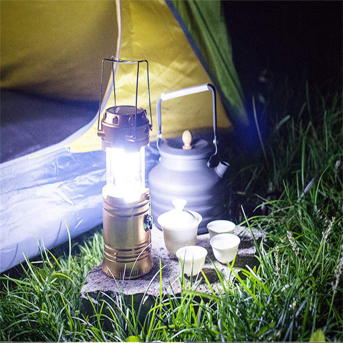 Nachtszenen: Laterne, Kessel, Tassen und Teeservice auf einem Stein. Beleuchtet vom Laternenlicht, in der Nähe eines Zeltes.