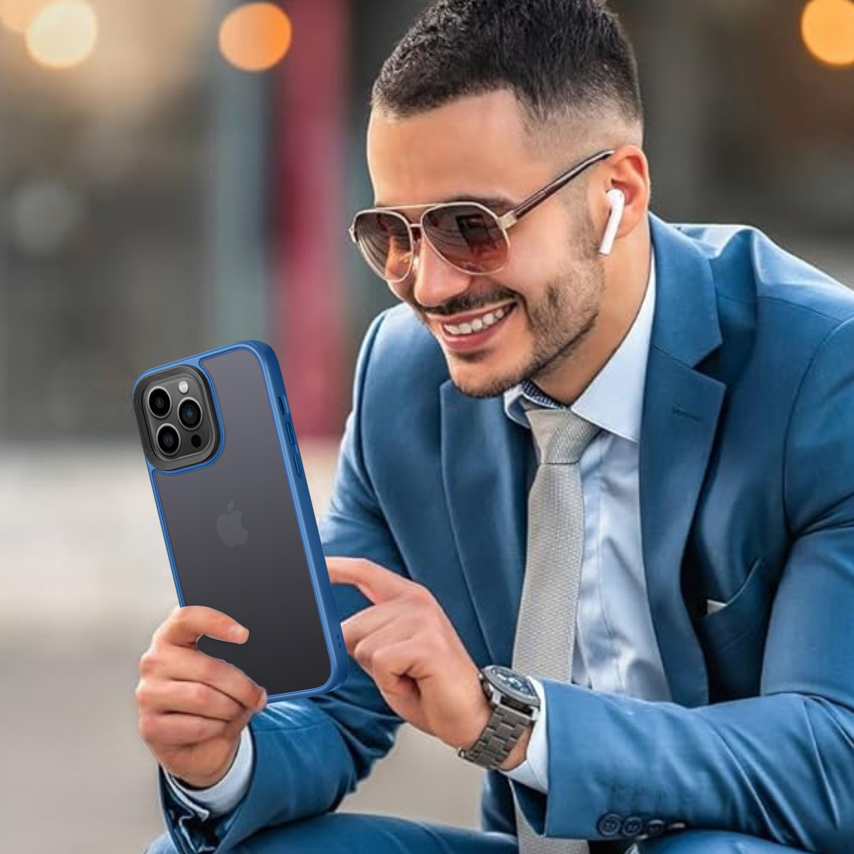 Mann im blauen Anzug hält ein Telefon mit blauer Hülle. Er lächelt.