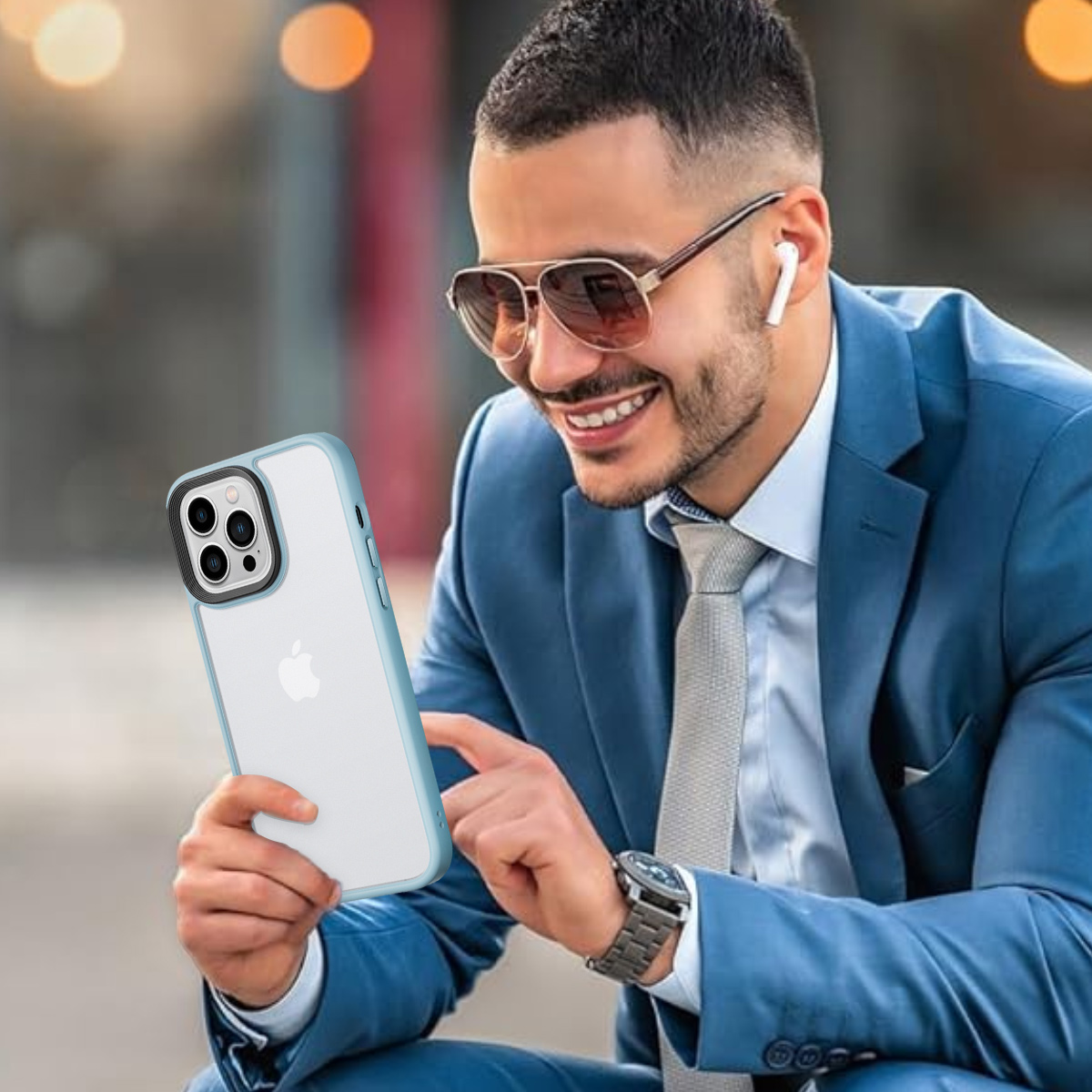 Mann im blauen Anzug lächelt, hält ein Telefon mit Hülle und trägt Sonnenbrille und Ohrhörer.