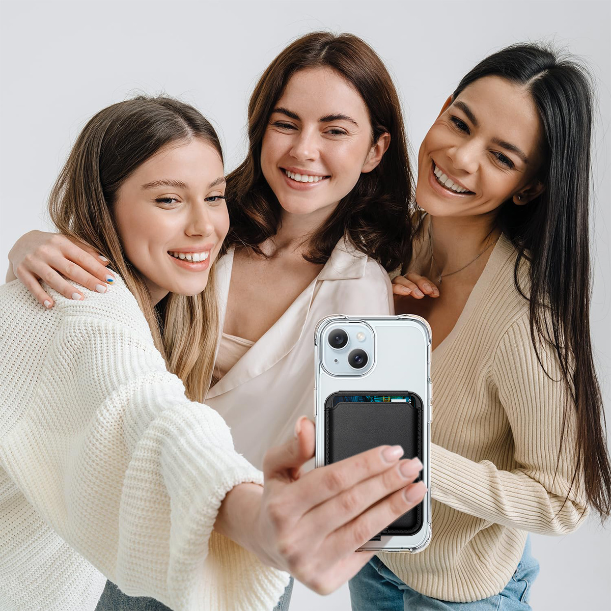 Drei Frauen machen ein Selfie mit einem Telefon. Eine Handyhülle mit Kartenhalter ist sichtbar.