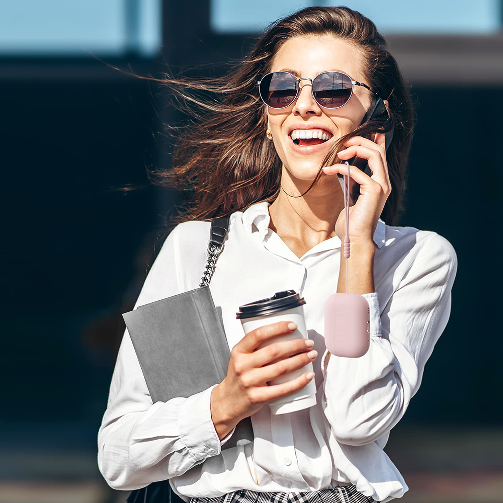 Eine Frau mit Sonnenbrille lächelt, telefoniert und hält eine Kaffeetasse und ein Notizbuch.