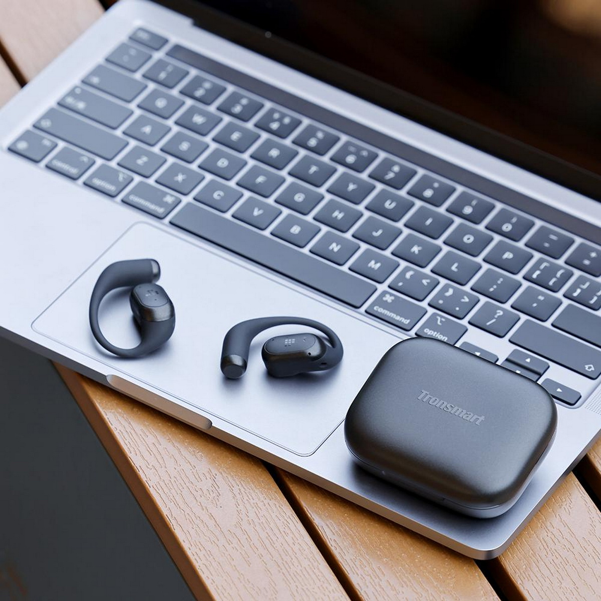 Ohrhörer und ein Ladecase auf einer Laptop-Tastatur. Das Case hat den Markennamen Tronsmart.