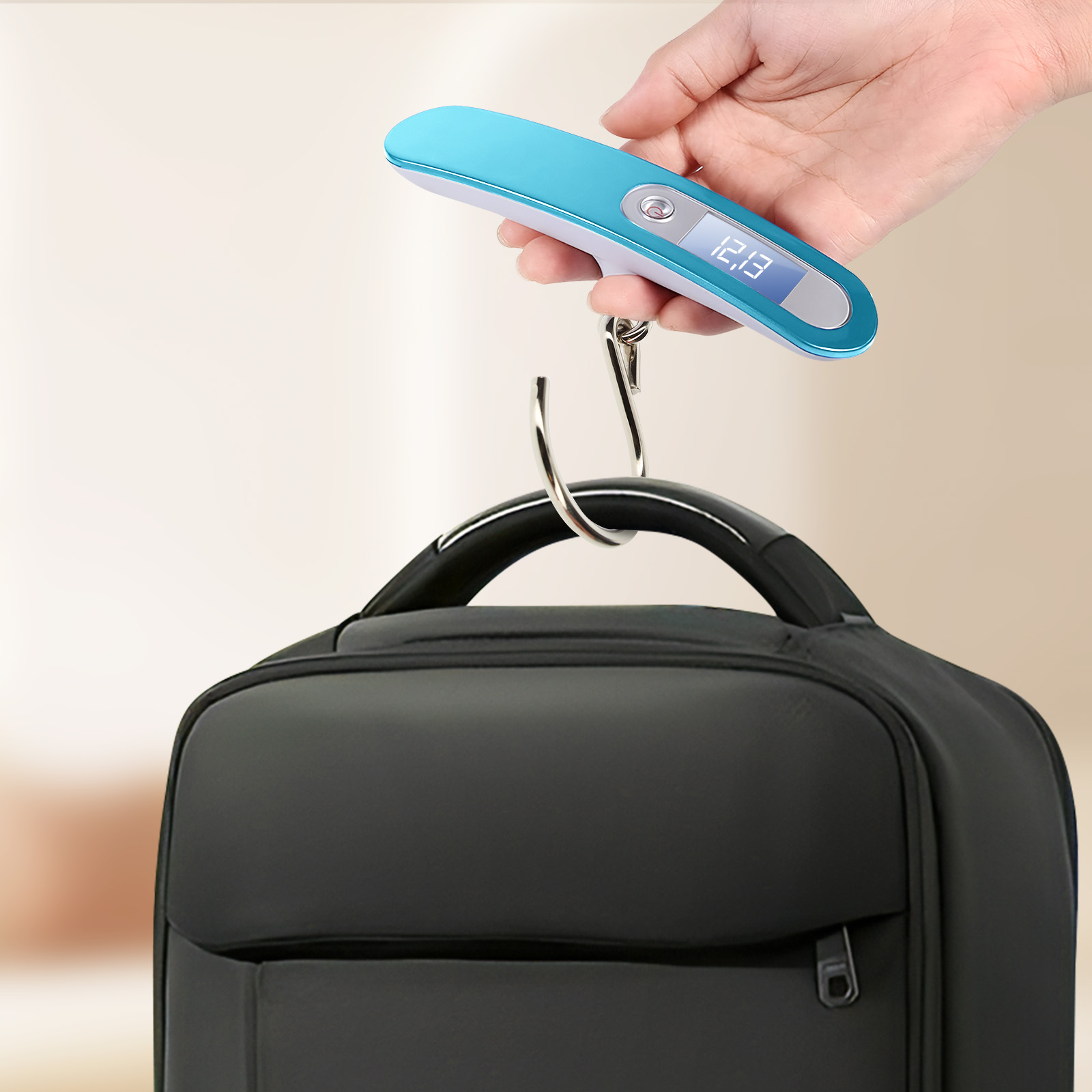 Eine Hand hält eine blaue Digitalwaage, die einen schwarzen Rucksack wiegt. Die Waage zeigt 12,3 an.