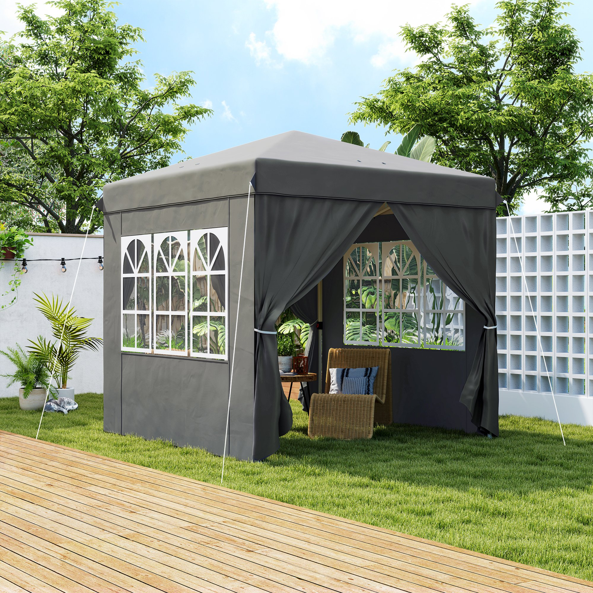 Grauer Pavillon mit weißen Fensterrahmen, auf Gras, mit Stuhl und Pflanzen.