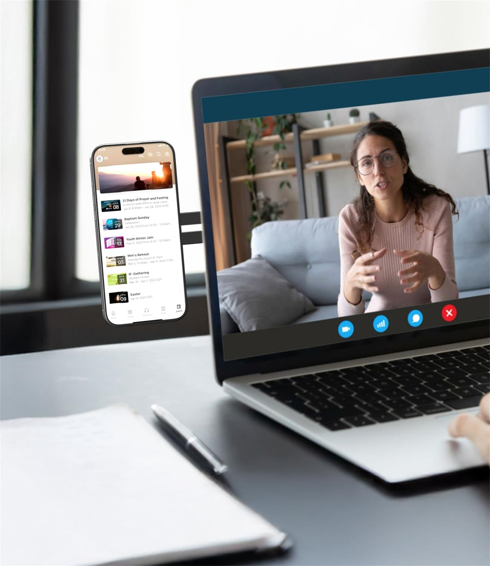Laptop mit Videoanruf und Smartphone mit App-Oberfläche. Beide Geräte auf einem Schreibtisch.