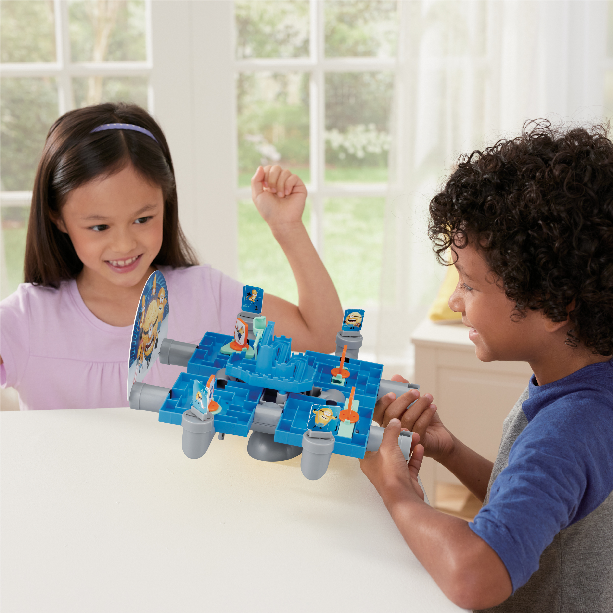Twee kinderen spelen een Minions-bordspel. Het spel is een blauw doolhof met Minion-personages.