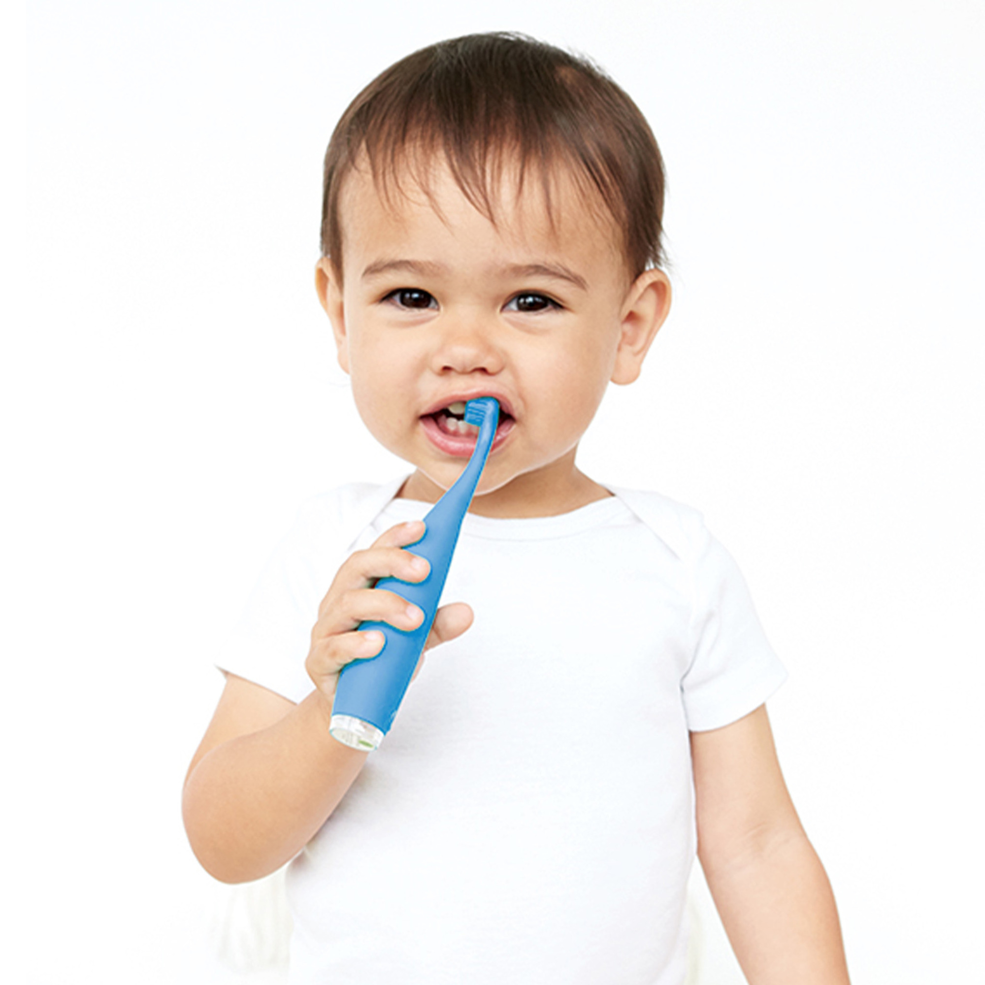 Un bebé cepillándose los dientes con un cepillo azul. El bebé usa un body blanco, fondo blanco.