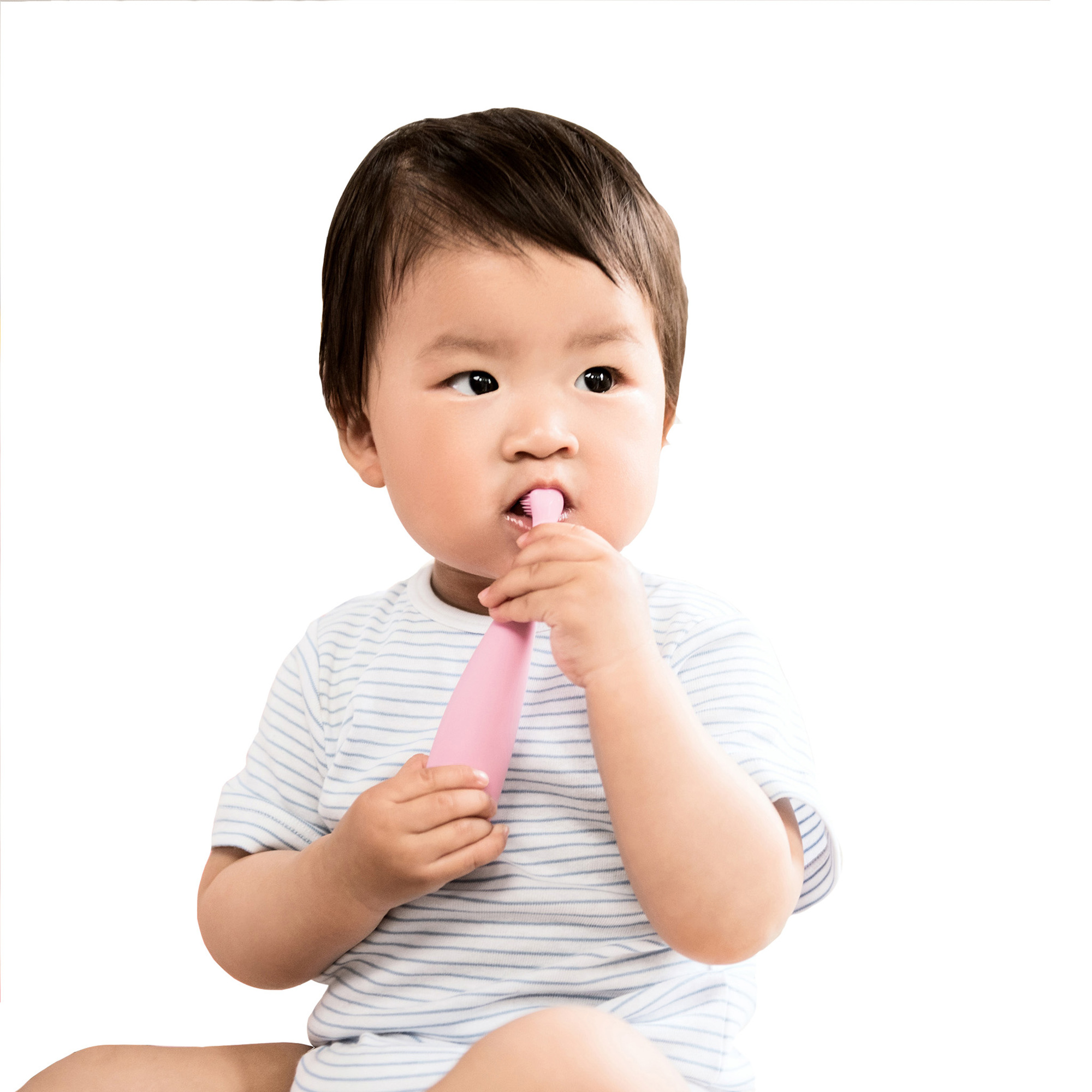 Un bebé sosteniendo un cepillo de dientes rosa en la boca. Está sobre un fondo blanco.