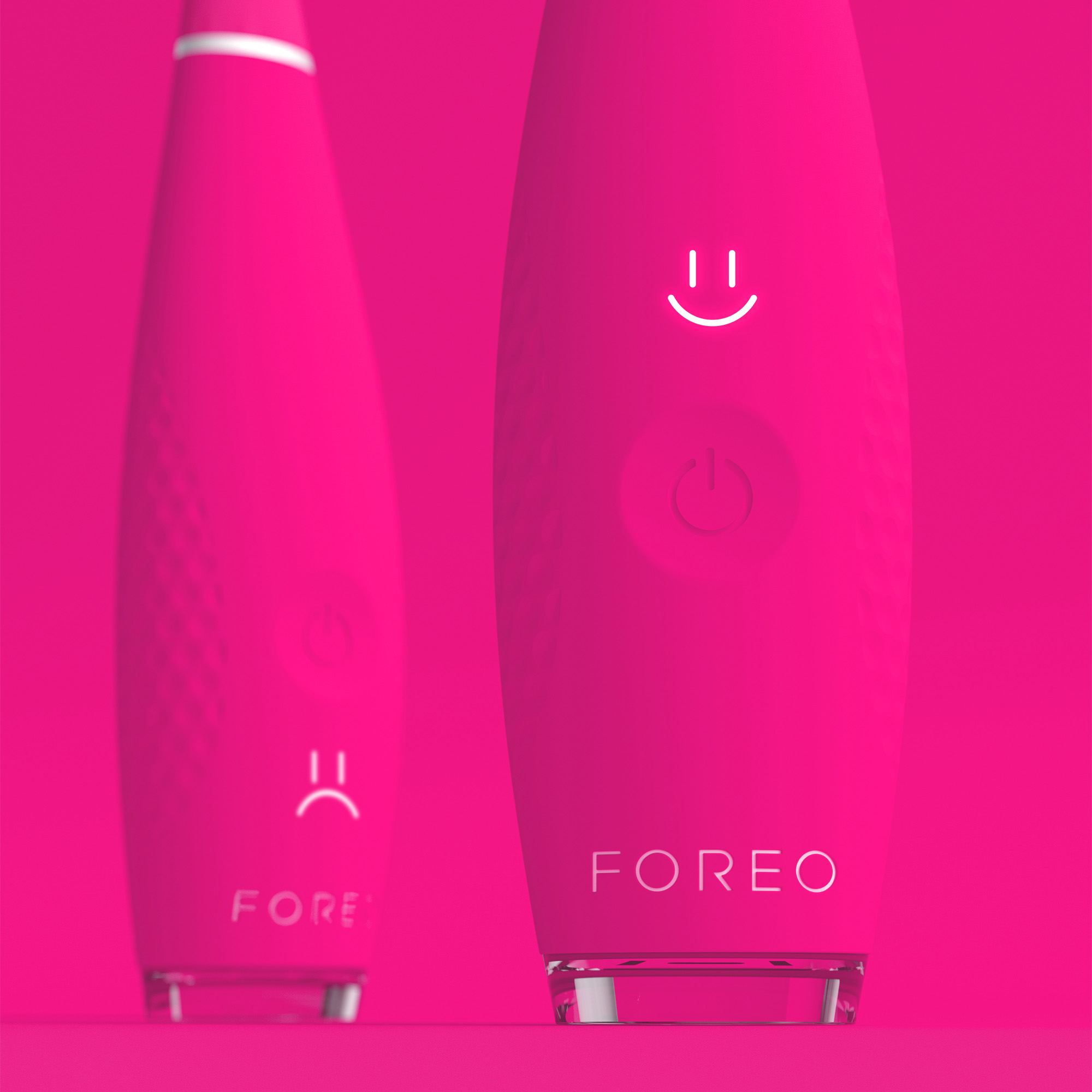Dos cepillos FOREO rosas. Uno muestra una cara feliz, otro una cara triste, contra un fondo rosa.