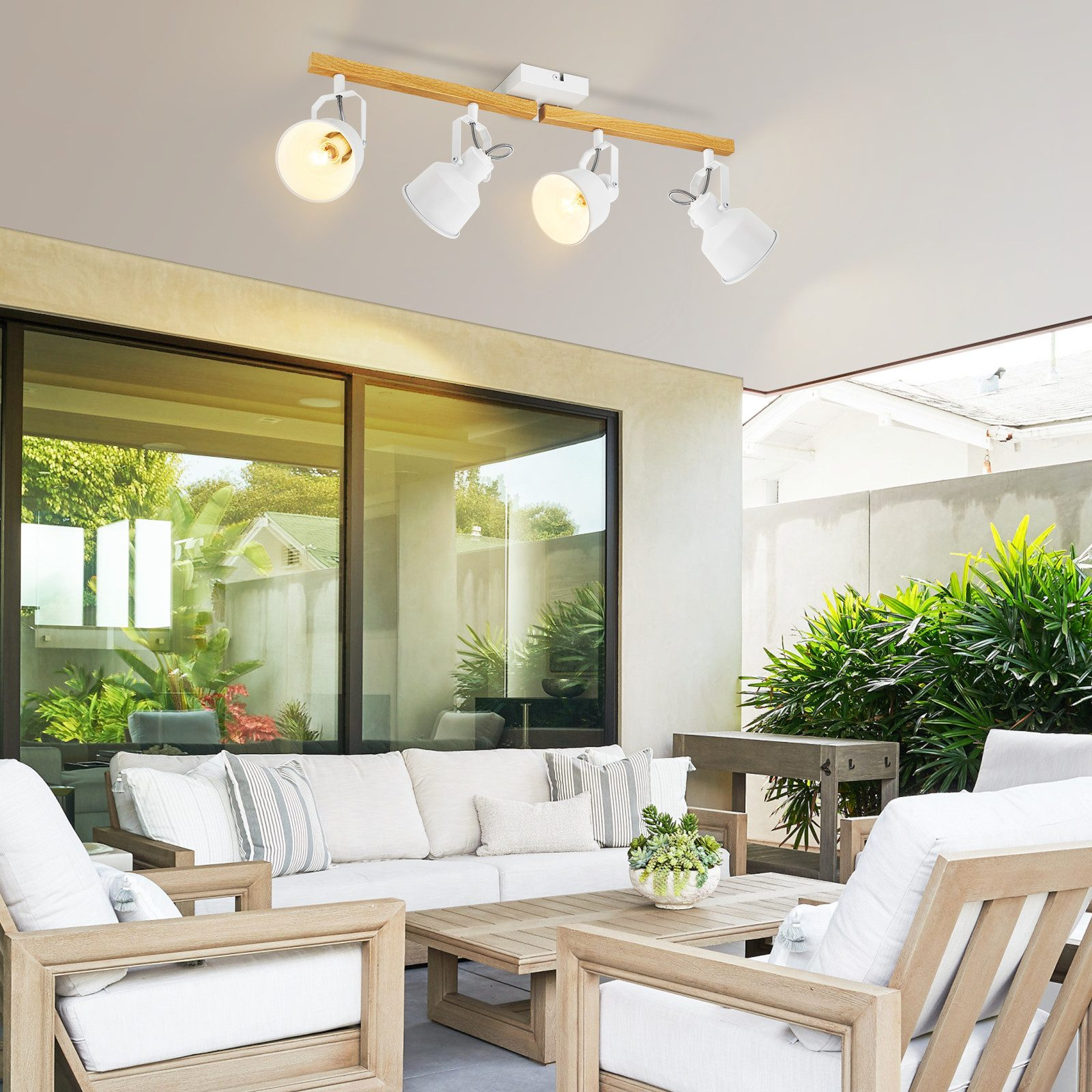 Ujęcie z zewnątrz patio. Białe meble z roślinami i szklane drzwi.