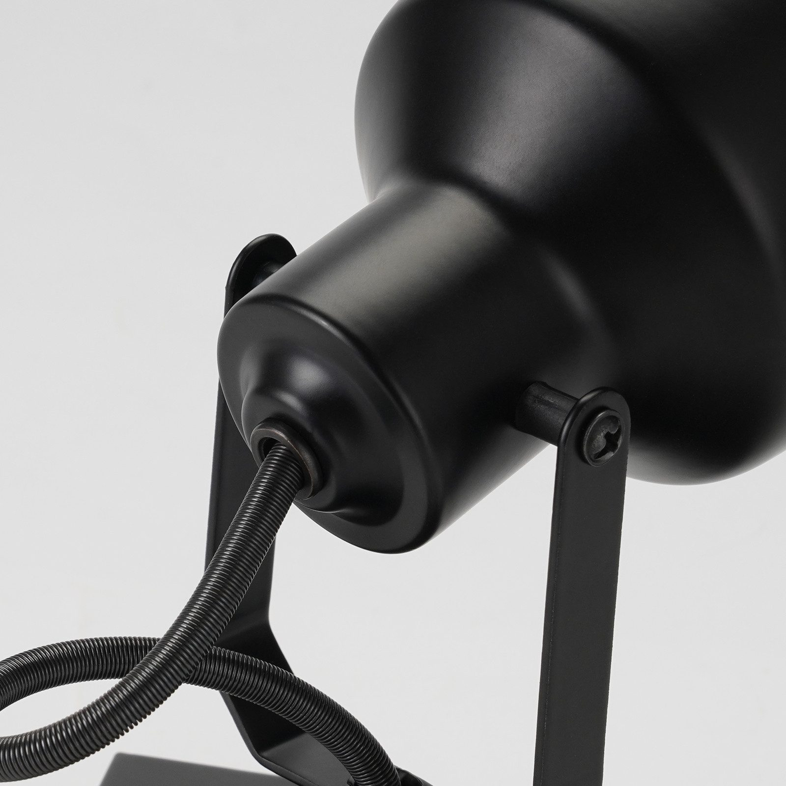 Zbliżenie czarnego reflektora, pokazujące kabel połączeniowy. Tło jest białe.