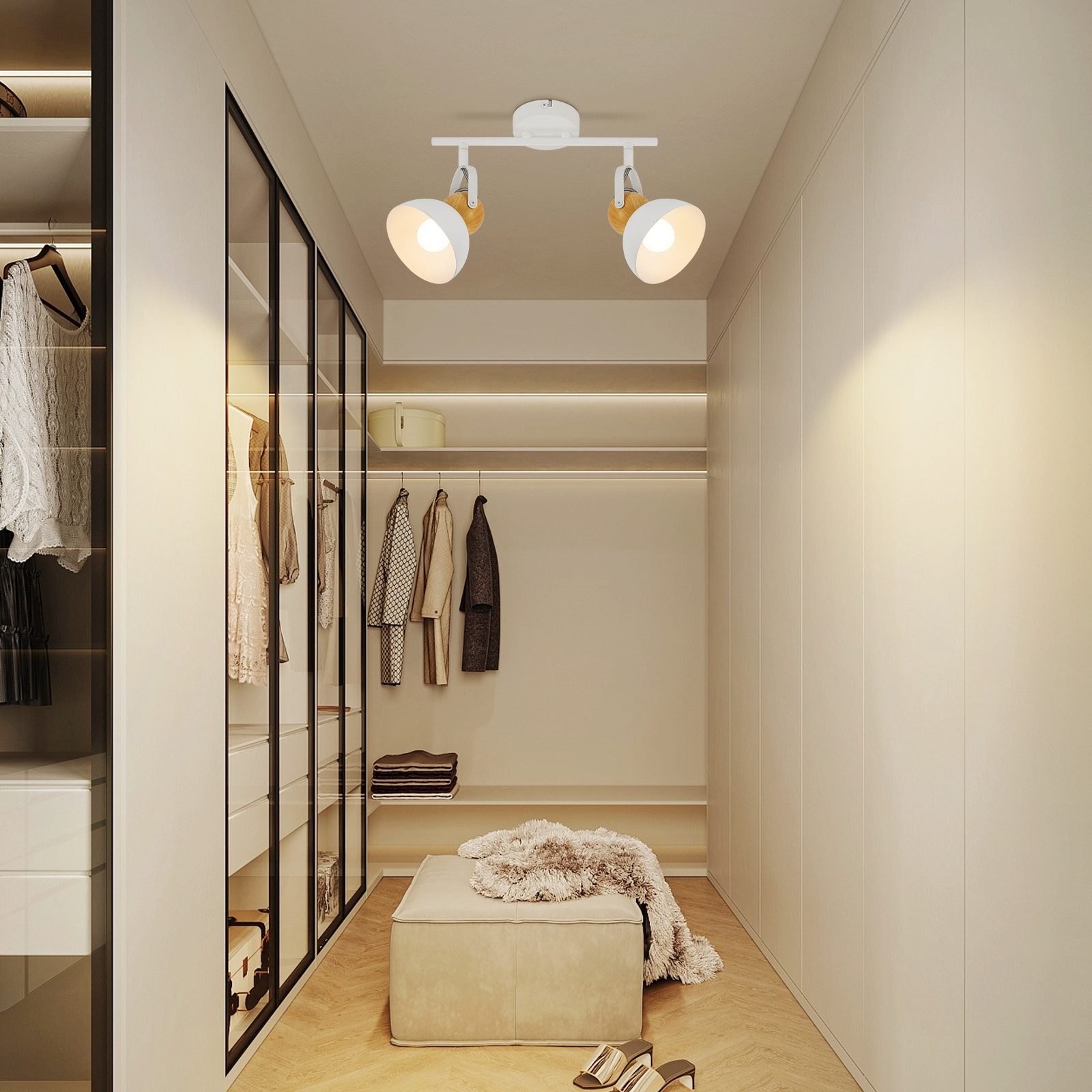 Garderoba z białymi ścianami, oświetleniem, ubraniami i ławką z puszystym dywanem.