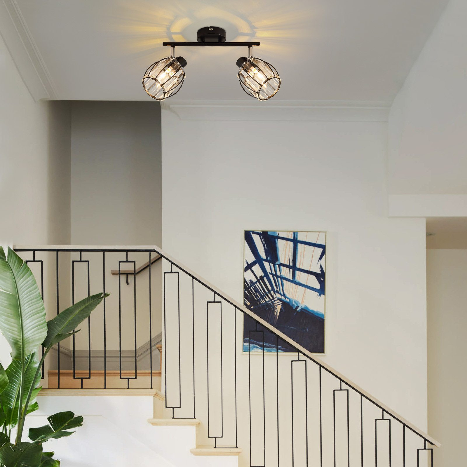 Korytarz ze schodami, lampa sufitowa z dwoma reflektorami oświetla scenę.