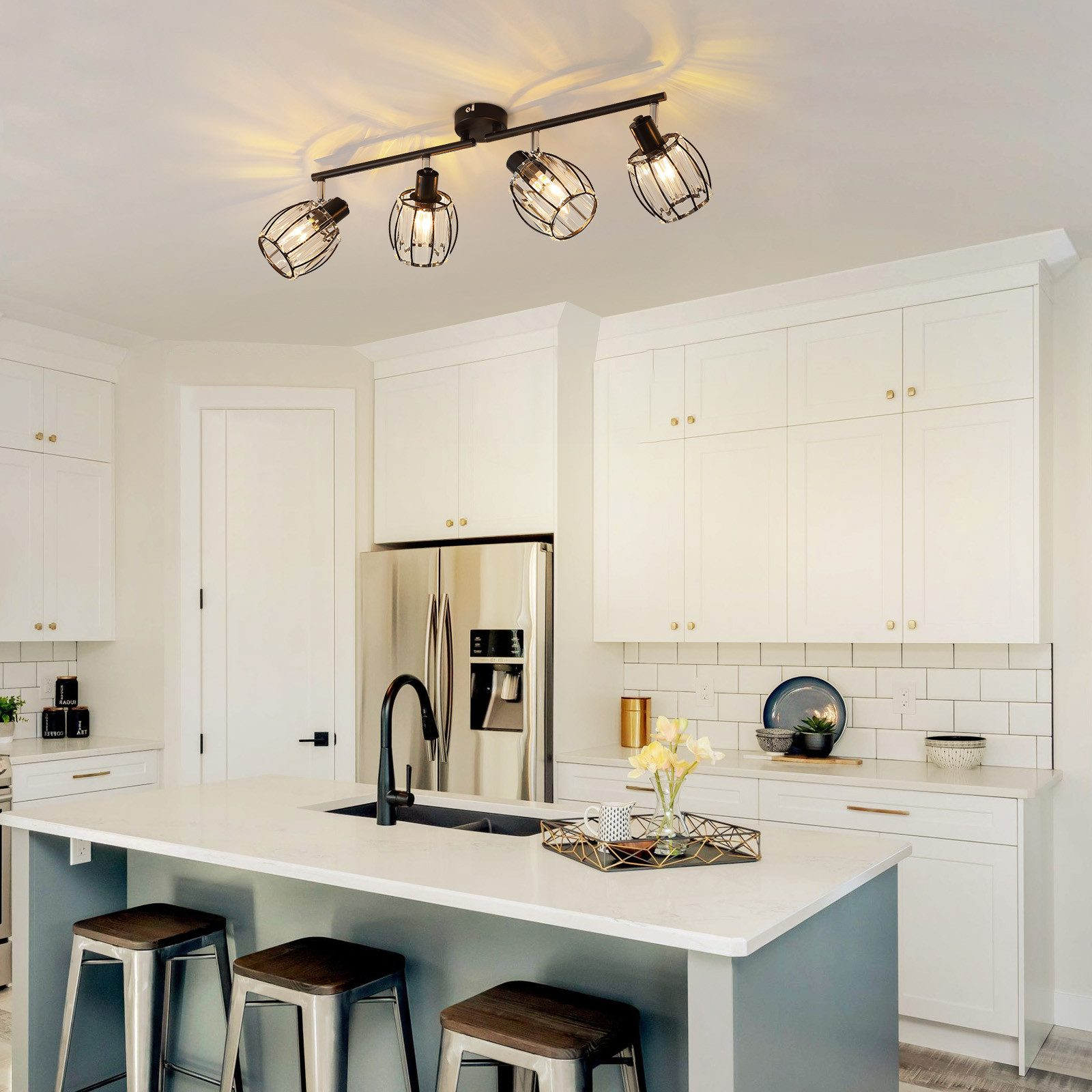 Kuchnia z oświetleniem. Kuchnia ma białą wyspę, szafki i lodówkę ze stali nierdzewnej.